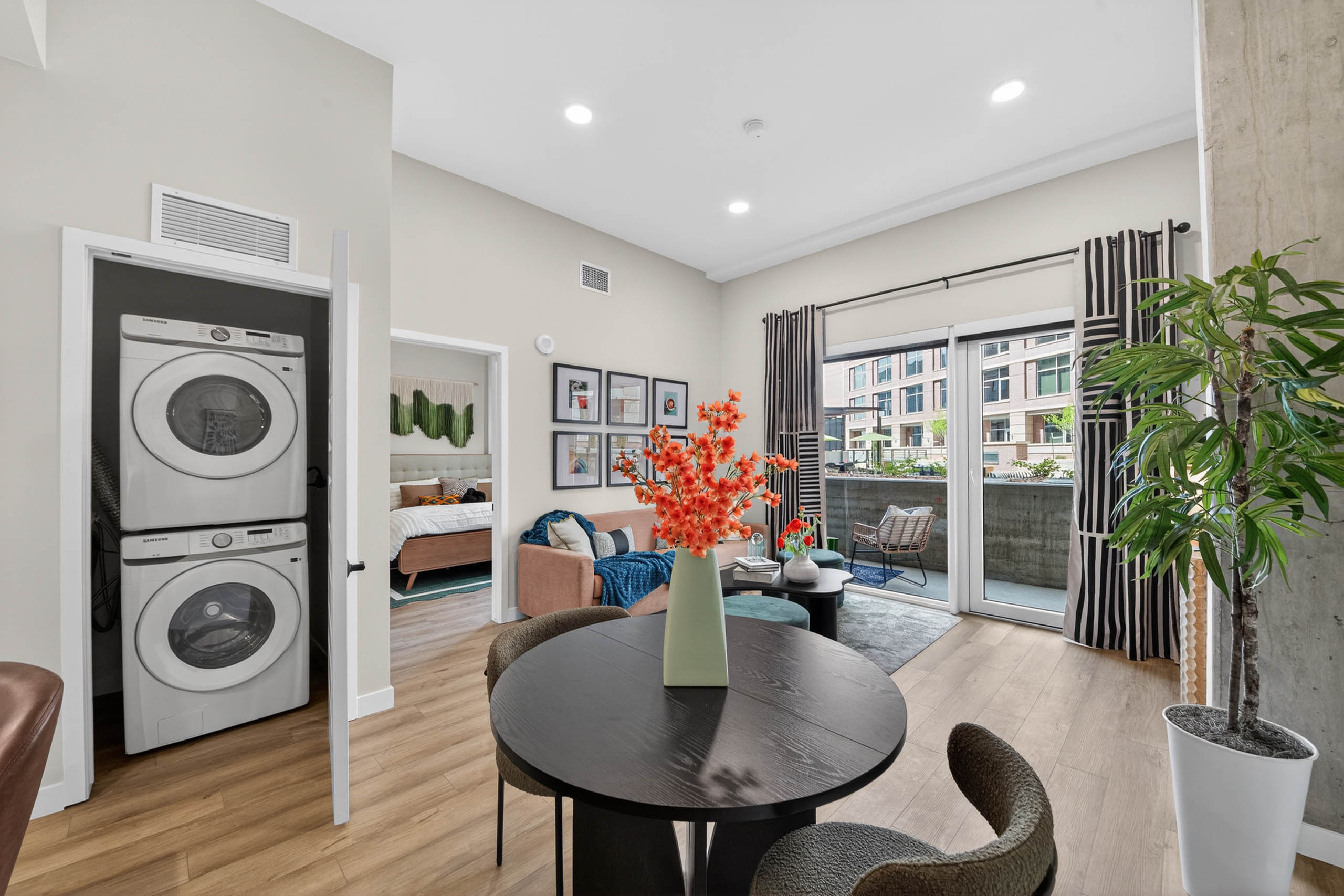 Dining area at AMLI Golden Triangle apartment with round table living room seating patio doors and in unit laundry closet