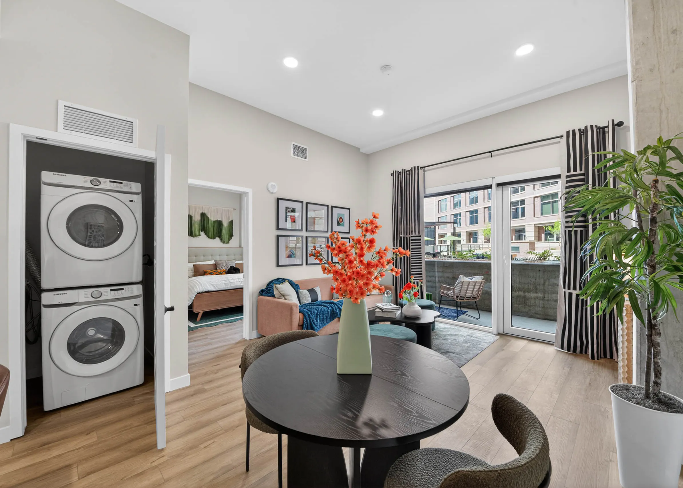 Dining area at AMLI Golden Triangle apartment with round table living room seating patio doors and in unit laundry closet