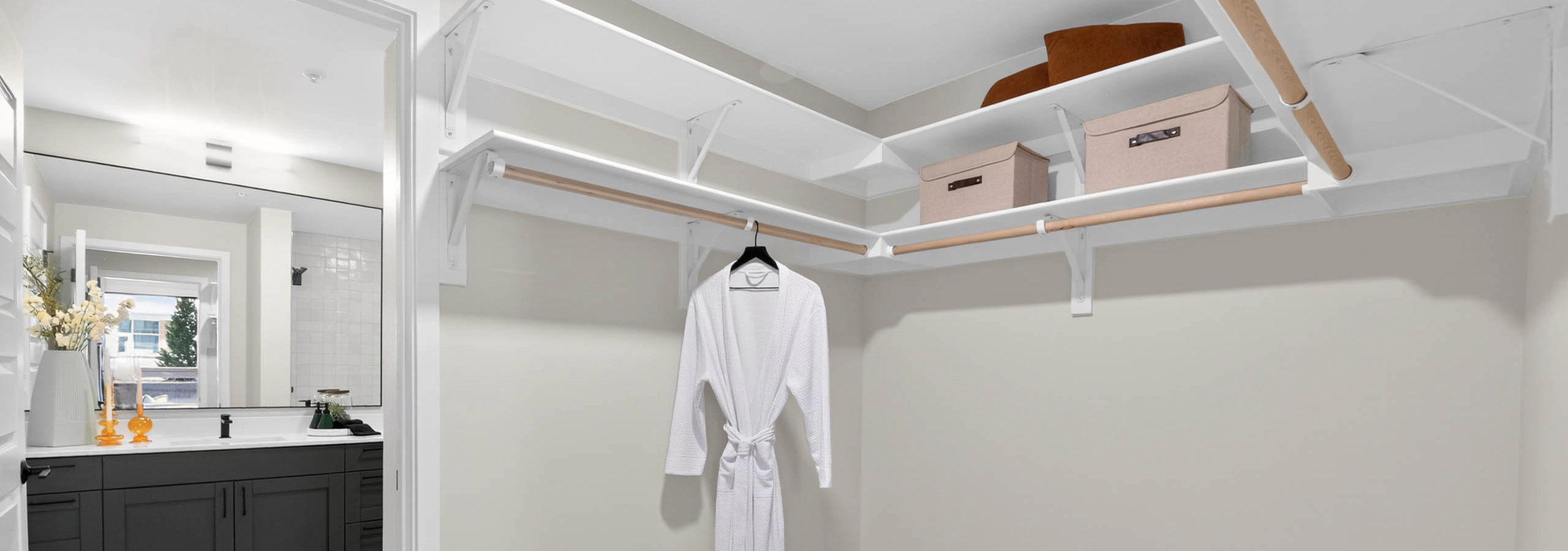 Walk in closet at AMLI Golden Triangle apartment with built in shelving hanging rods storage bins and wood flooring