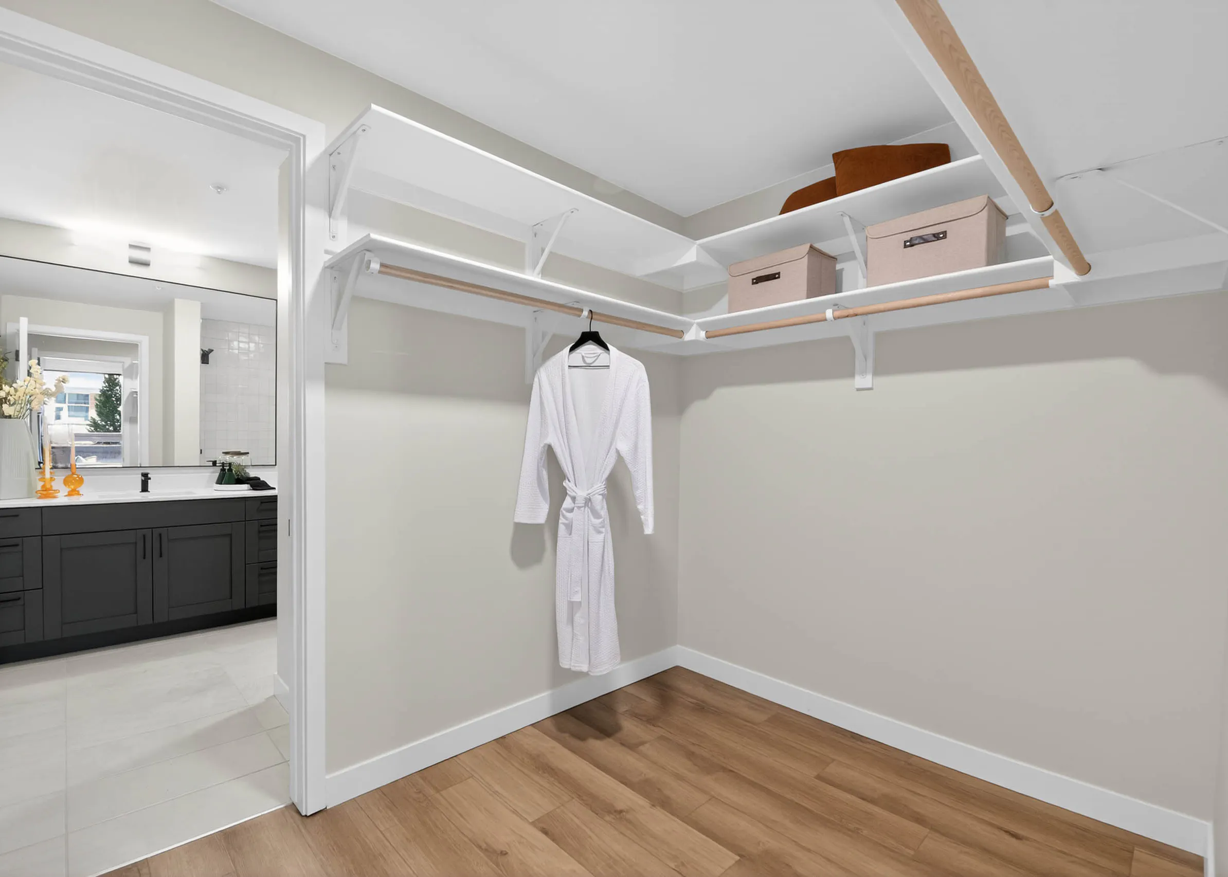 Walk in closet at AMLI Golden Triangle apartment with built in shelving hanging rods storage bins and wood flooring