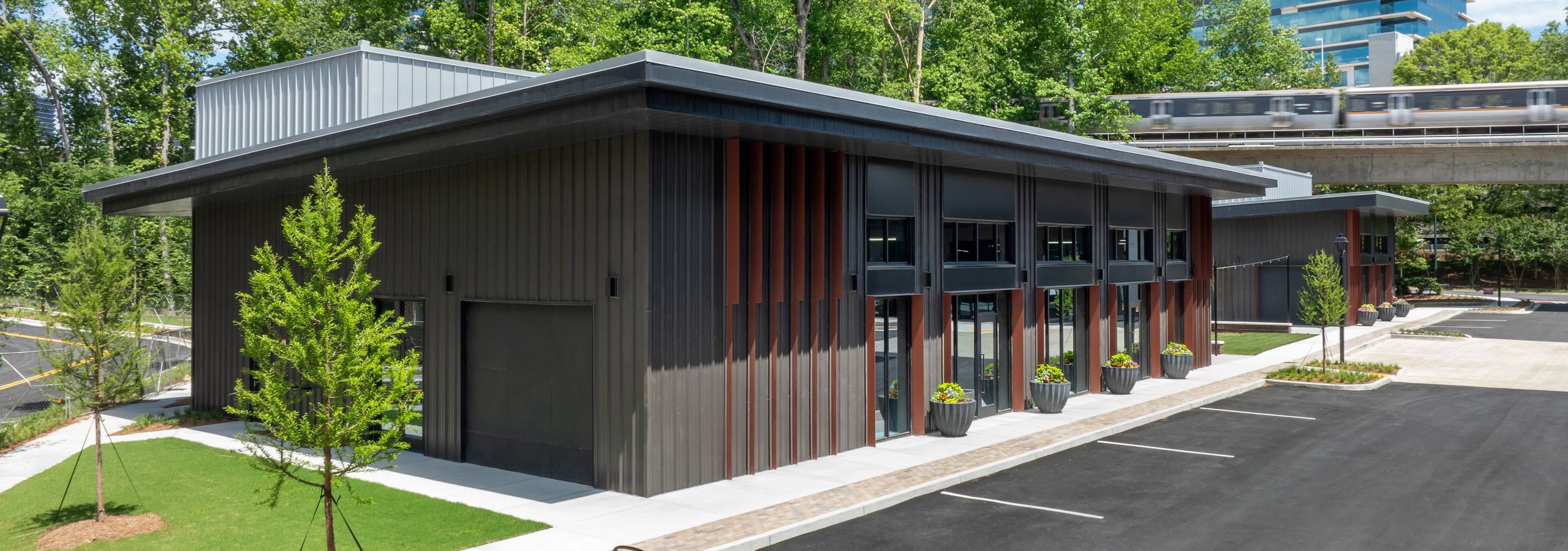 Retail village brown building with garage doors below train tracks at AMLI Brookhaven apartment community