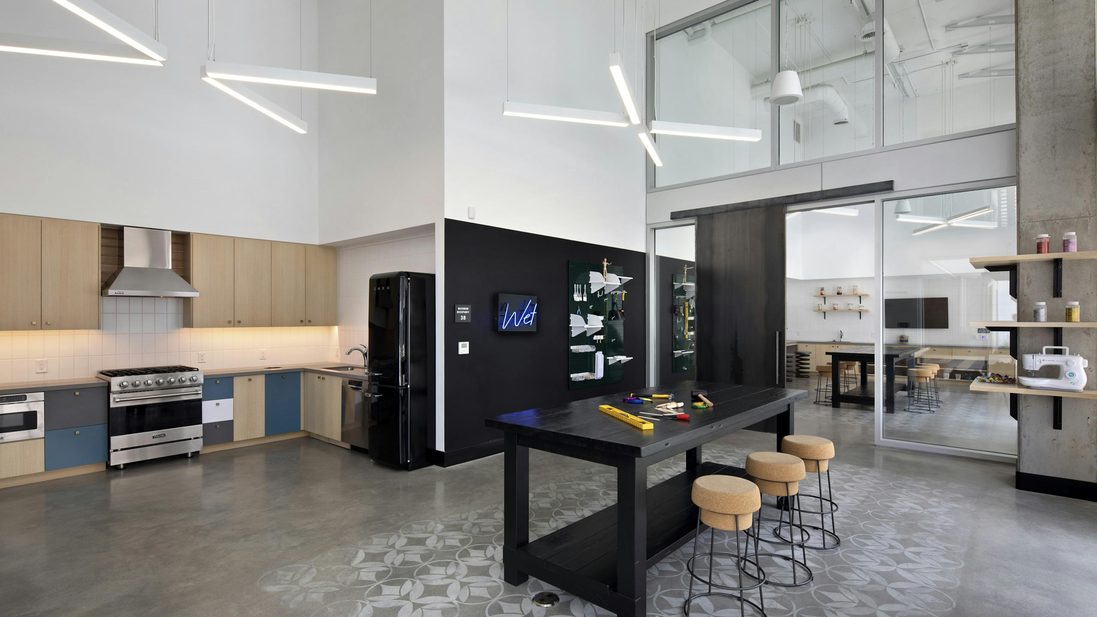 Arts and crafts maker space with catering kitchen and black table with three cork stools at AMLI Park Broadway apartments