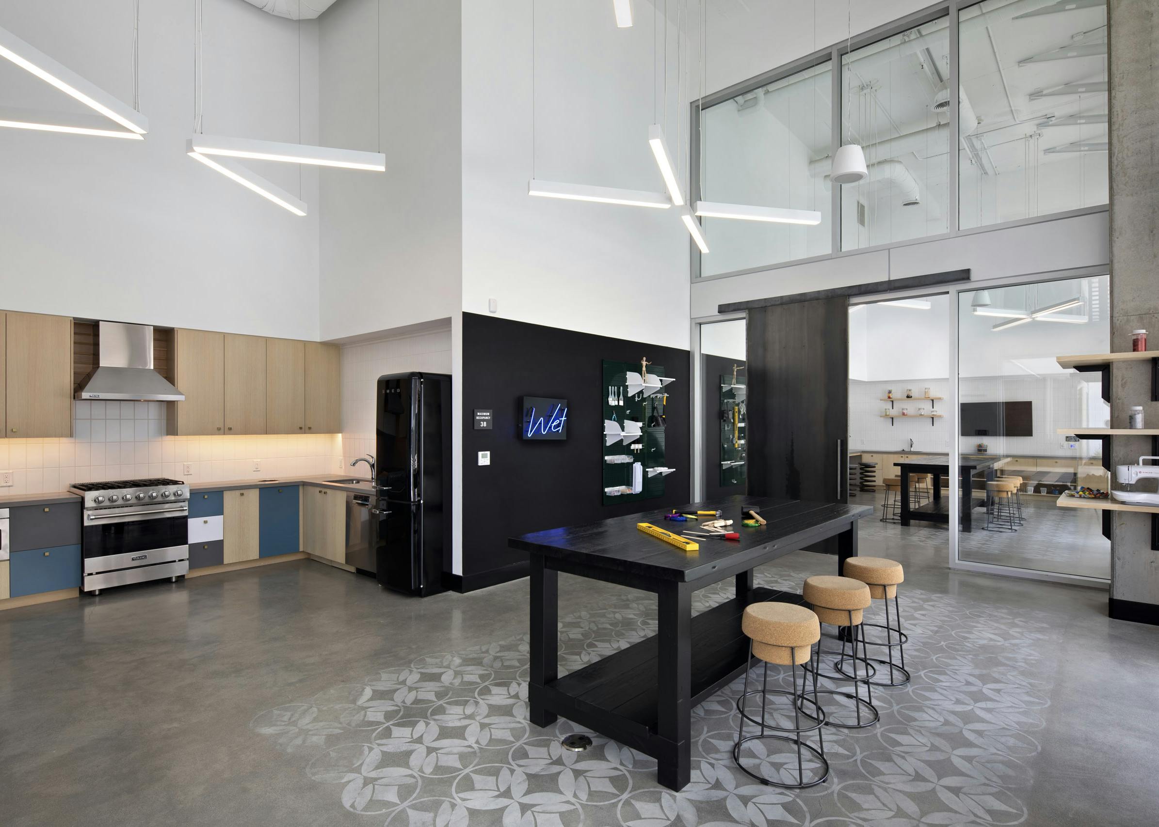 Arts and crafts maker space with catering kitchen and black table with three cork stools at AMLI Park Broadway apartments