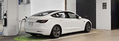 Electric vehicle charging station at AMLI Park Broadway apartments with white Tesla connected to charging station