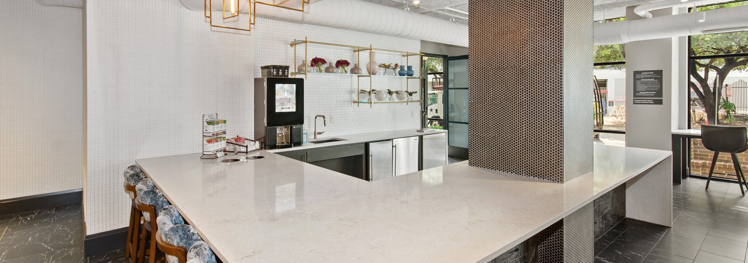 AMLI Quadrangle resident kitchen with Starbucks coffee machine and white quartz countertops on black tiled flooring