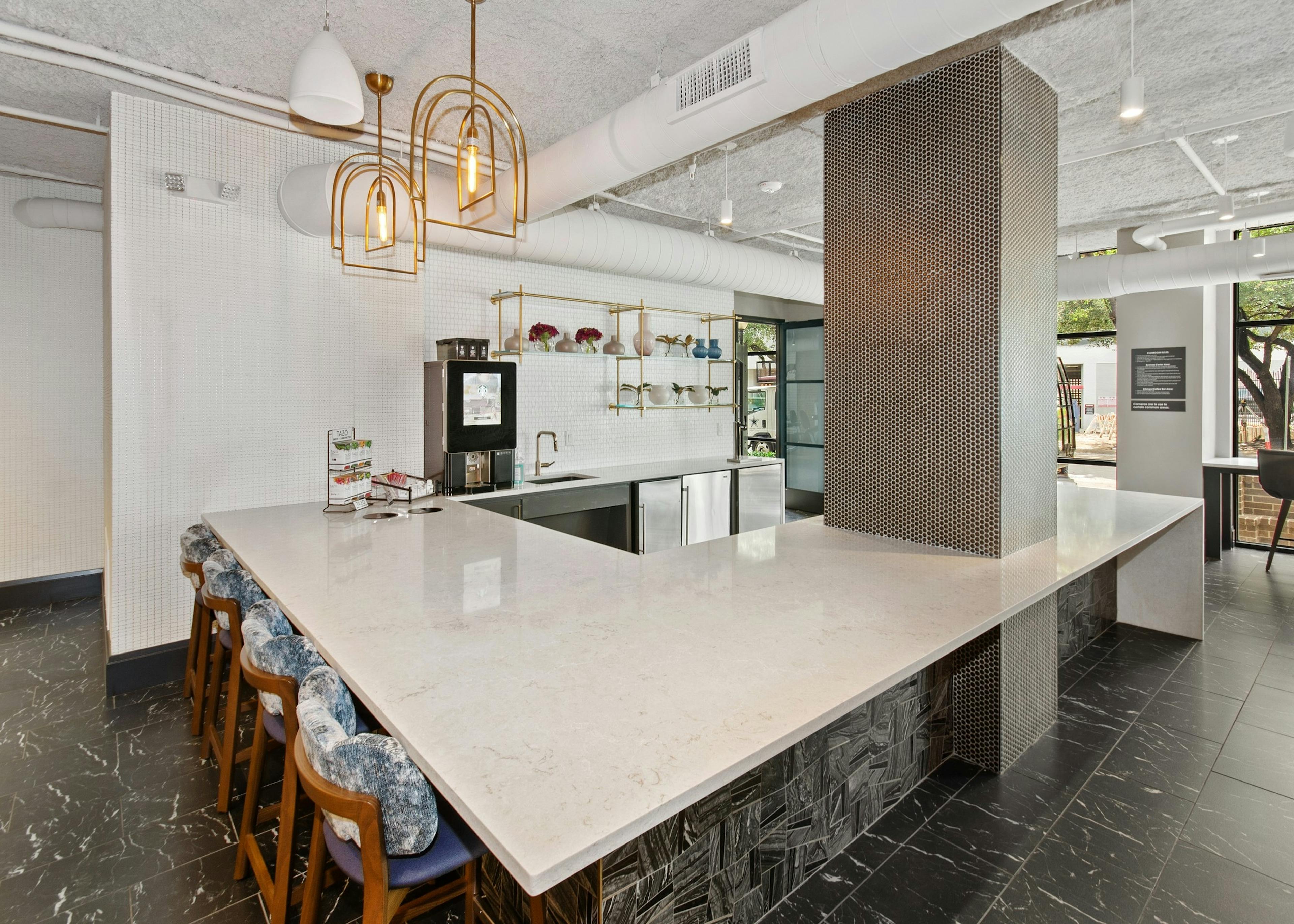 AMLI Quadrangle resident kitchen with Starbucks coffee machine and white quartz countertops on black tiled flooring