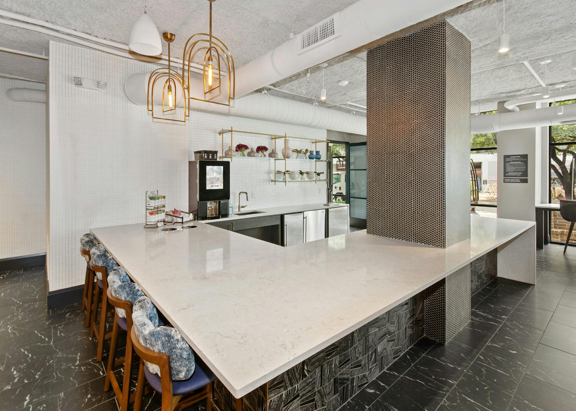 AMLI Quadrangle resident kitchen with Starbucks coffee machine and white quartz countertops on black tiled flooring