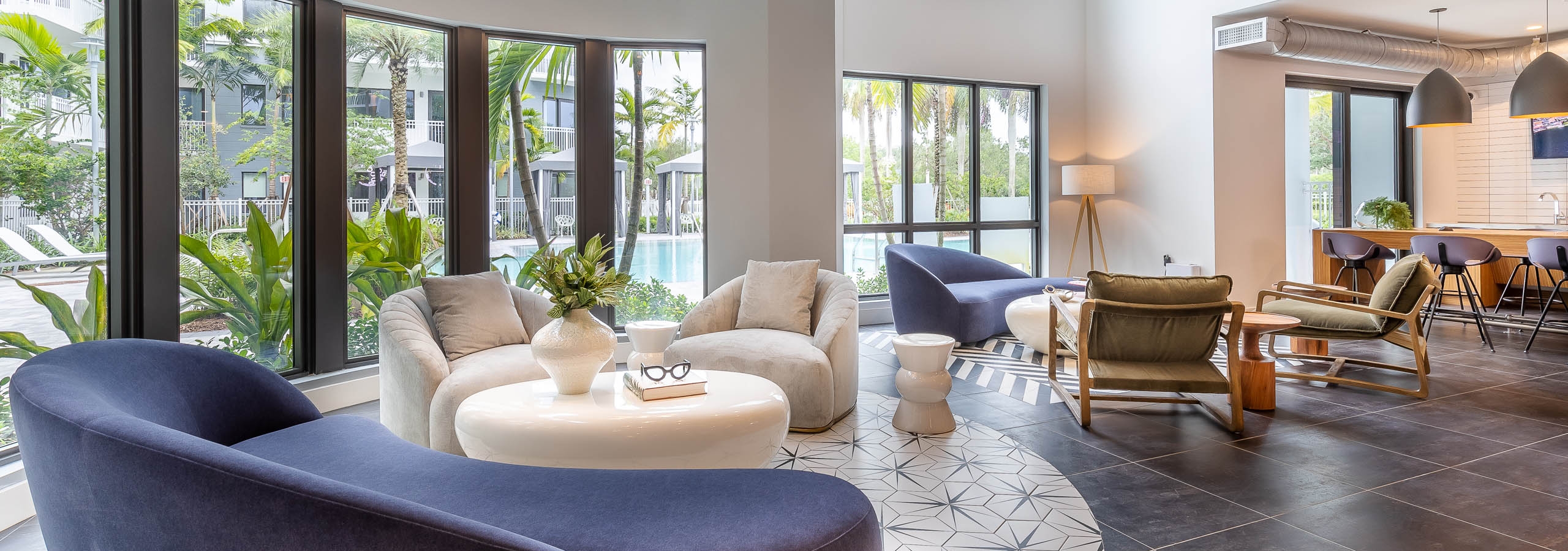 The resident lounge at AMLI Park west apartments with round inlay tile floor and modern seating with chandelier and pool view