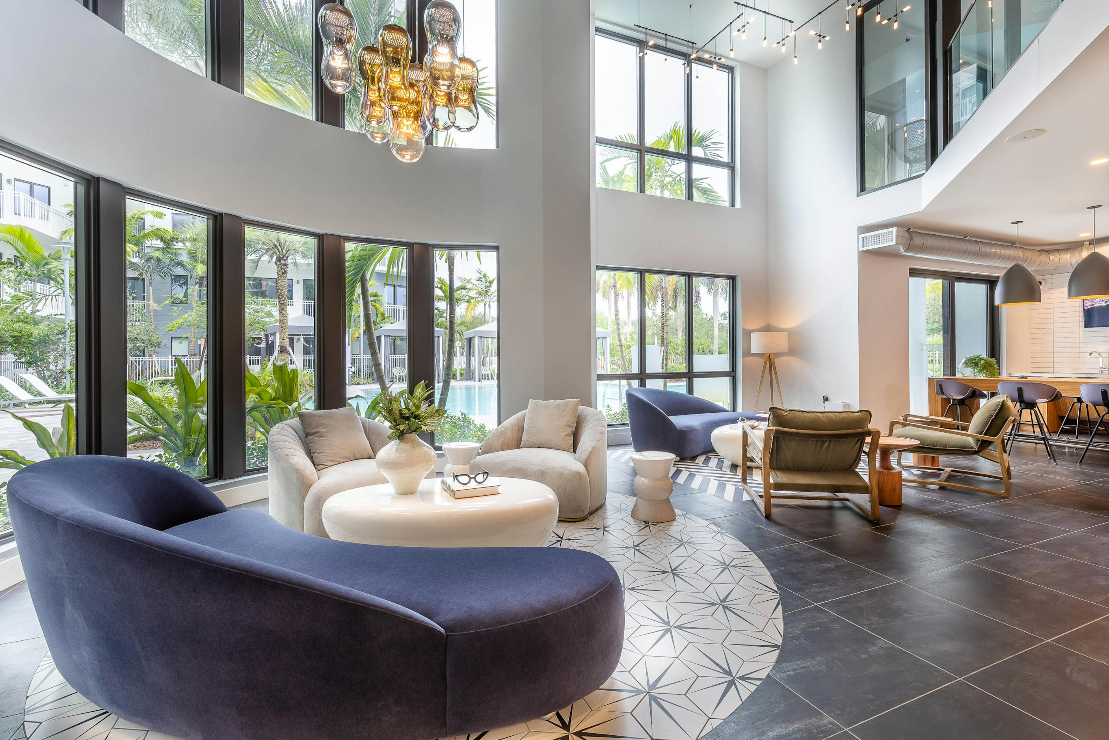 The resident lounge at AMLI Park west apartments with round inlay tile floor and modern seating with chandelier and pool view