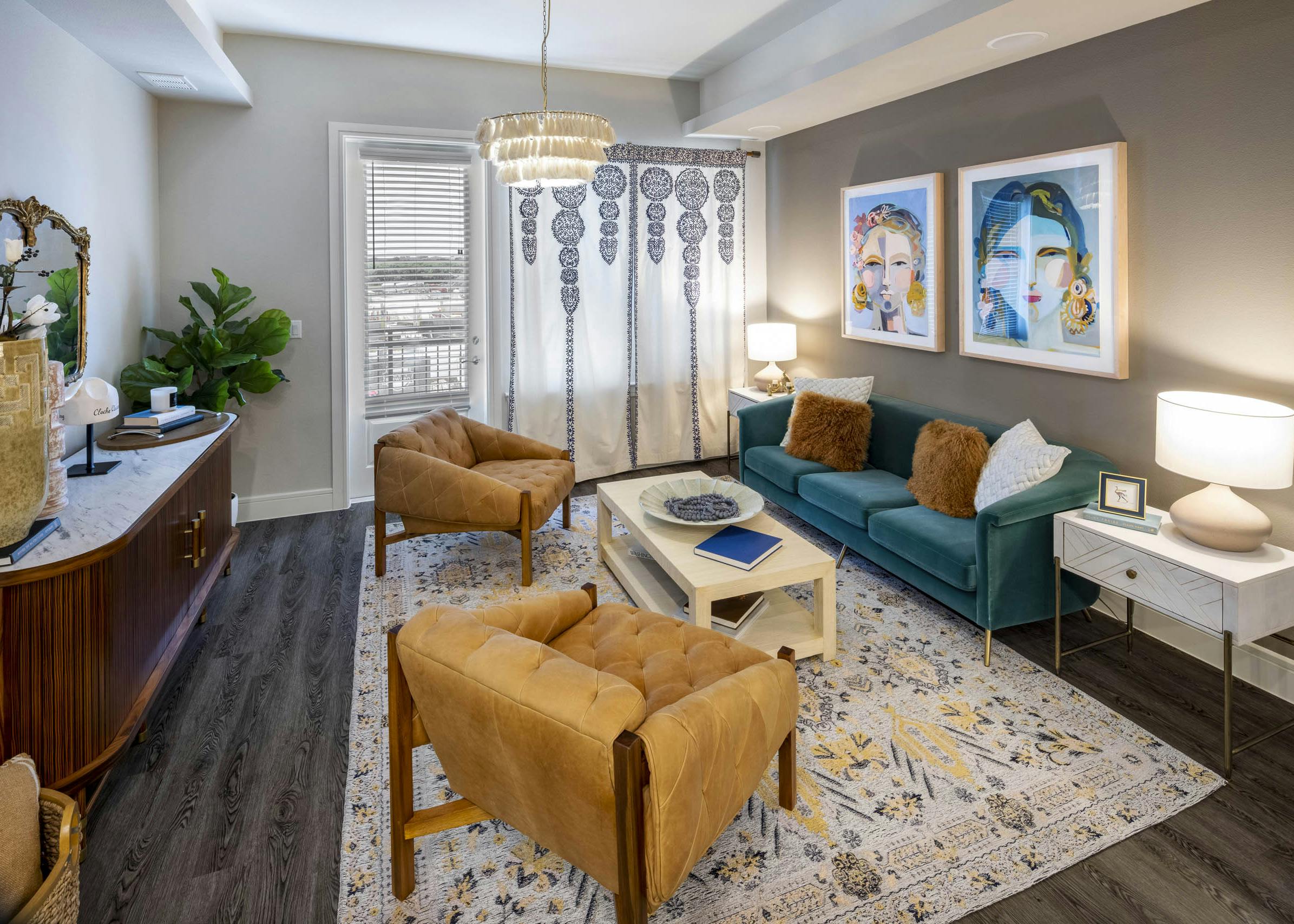 View of AMLI Lakeline apartment living room with dark orange leather chairs and a blue plush sofa on top of a colorful rug