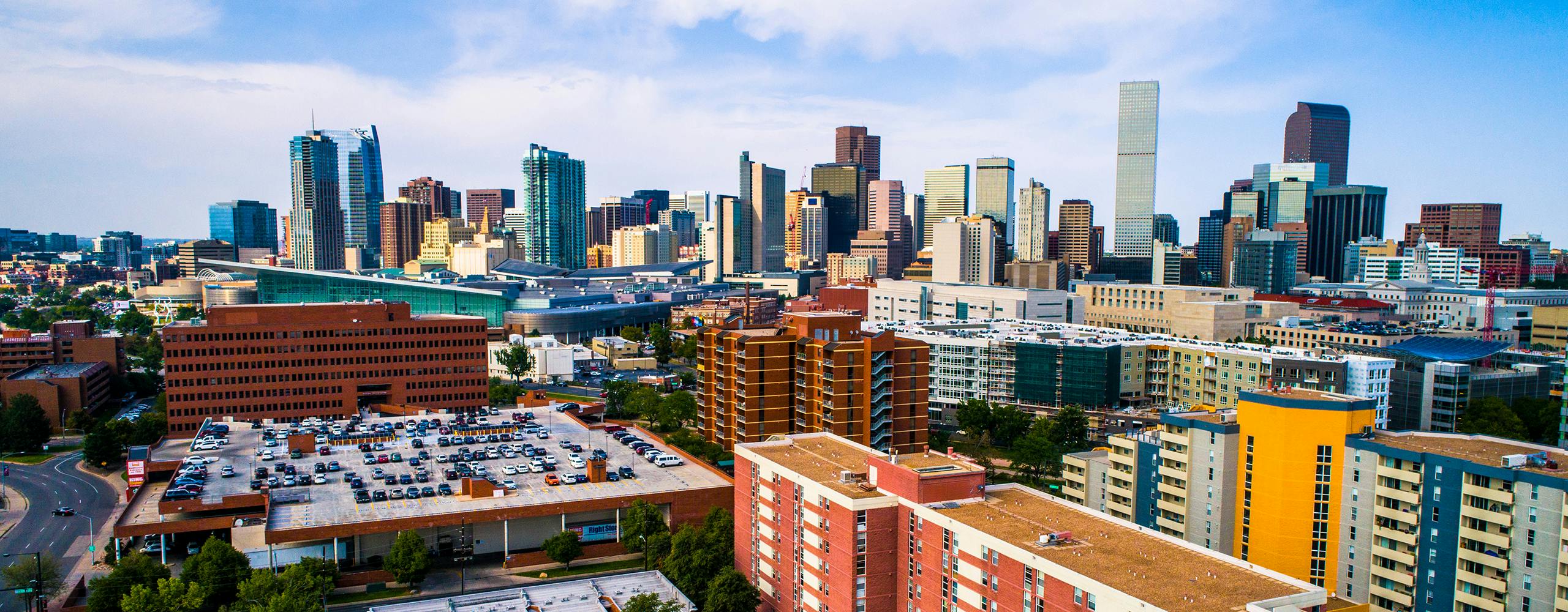 Aerial view of downtown Denver with colorful shorter buildings in the foreground and skyscrapers in the background