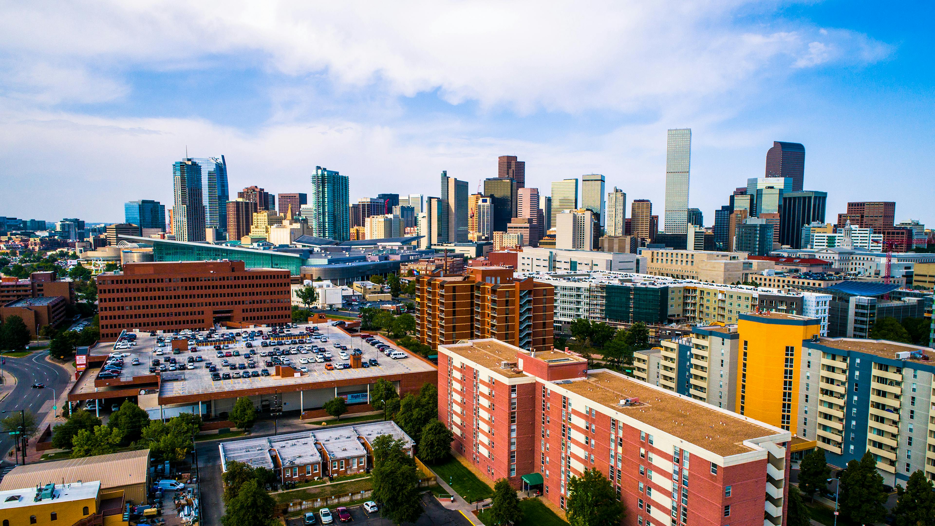 Aerial view of downtown Denver with colorful shorter buildings in the foreground and skyscrapers in the background 