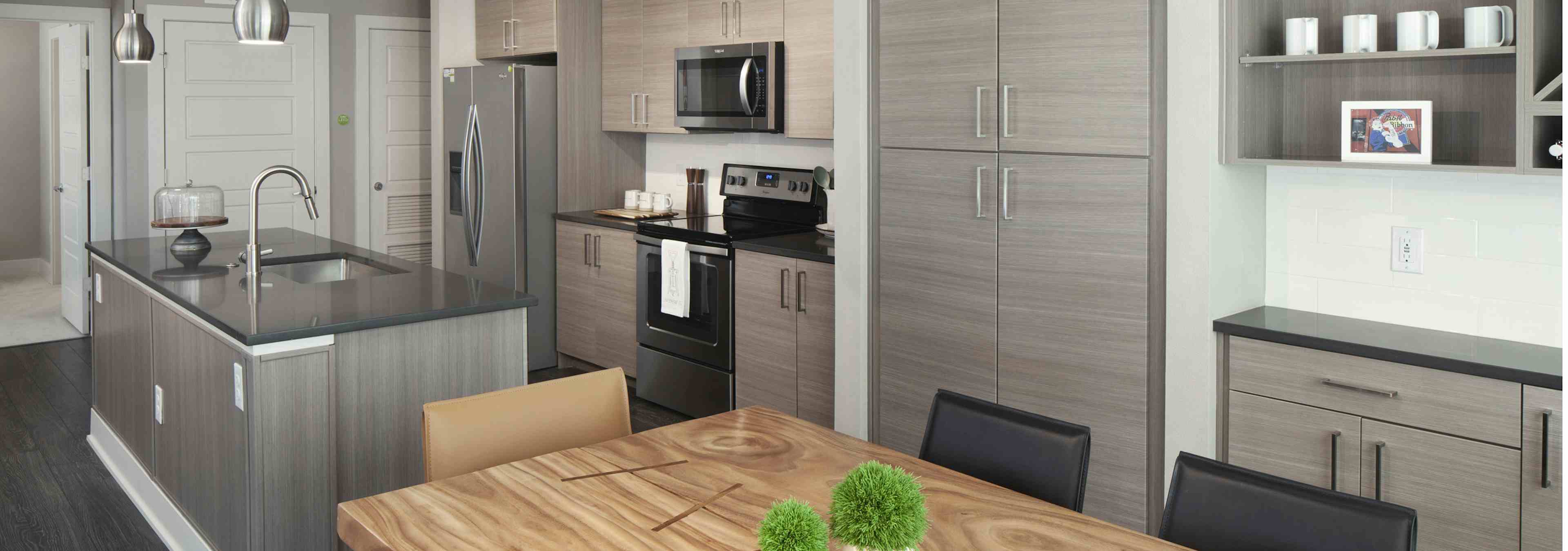 A kitchen at AMLI Riverfront Green apartment and view of dining table and kitchen island with closets in the background