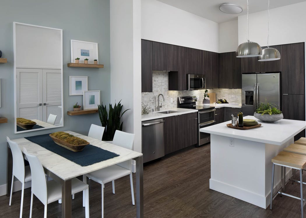 Interior of AMLI Uptown Orange apartment kitchen Island with quartz counters and stainless steel appliances and dining table
