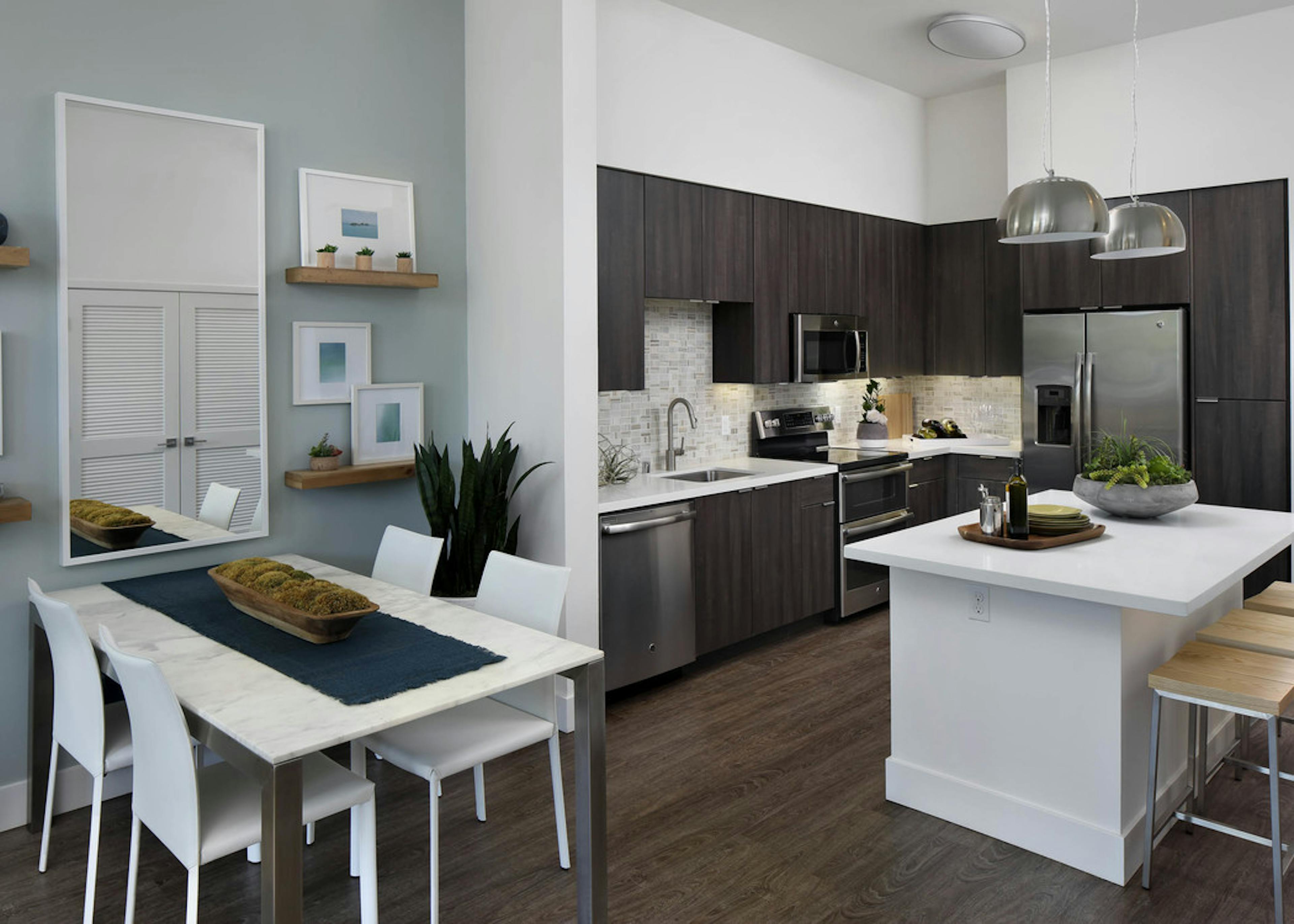 Interior of AMLI Uptown Orange apartment kitchen Island with quartz counters and stainless steel appliances and dining table