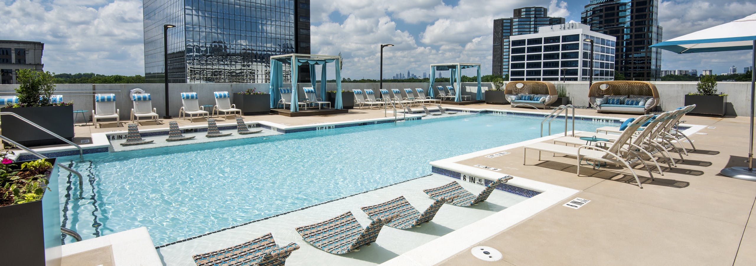 AMLI Lenox rooftop pool area on a sunny day with crystal blue water and lounge chairs and cabanas surrounding pool
