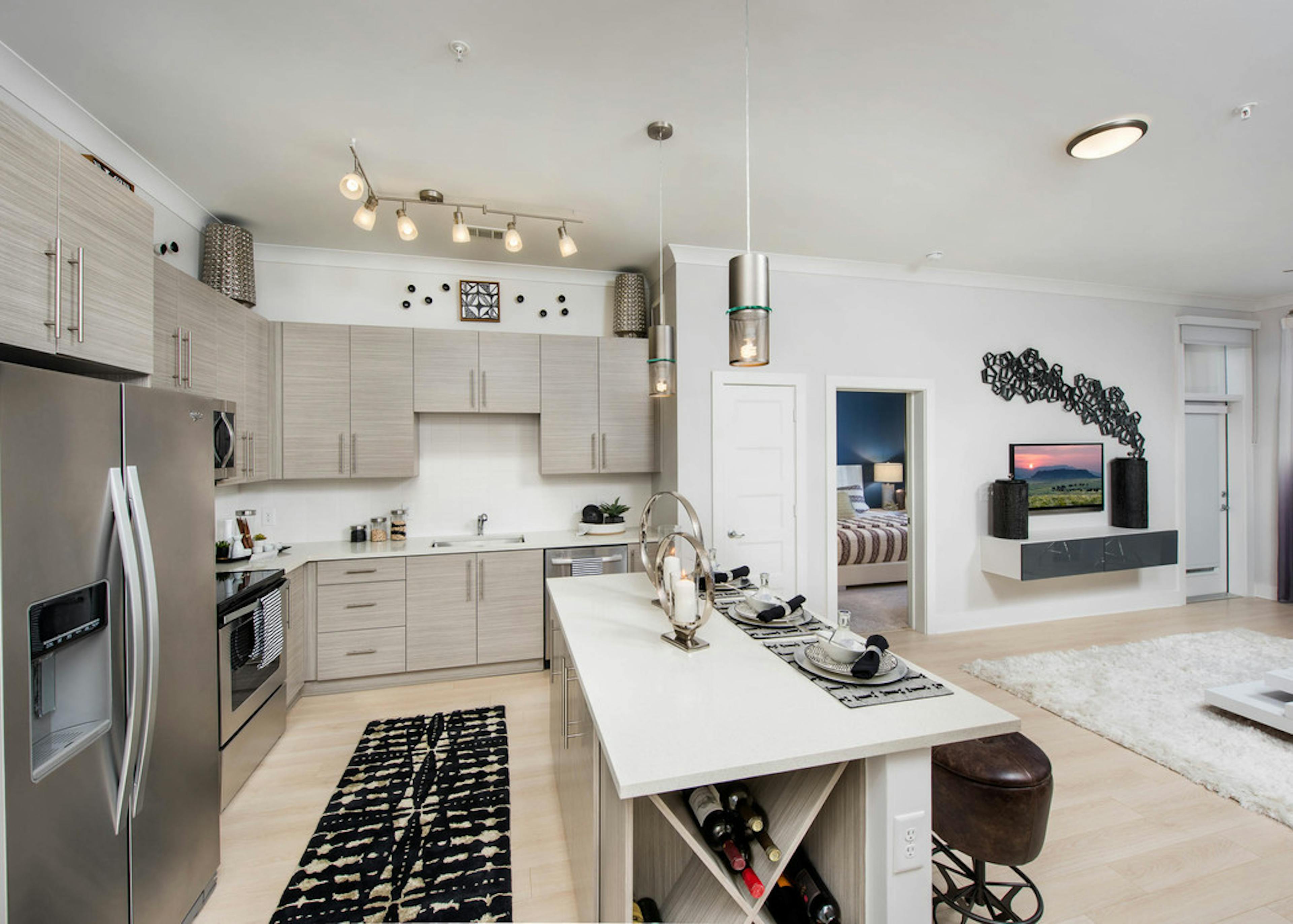 Kitchen at AMLI Buckhead with beige wooden cabinets and a spacious island with light wood floors and a black patterned rug