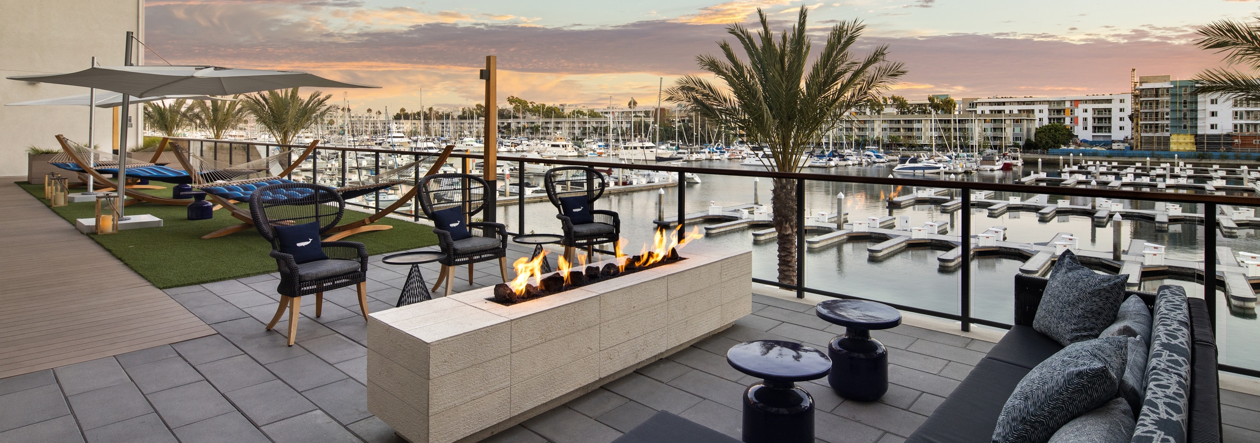 Dusk view of lounge deck with outdoor fireplace, oversized hammocks overlooking the marina at AMLI Marina Del Rey apartments