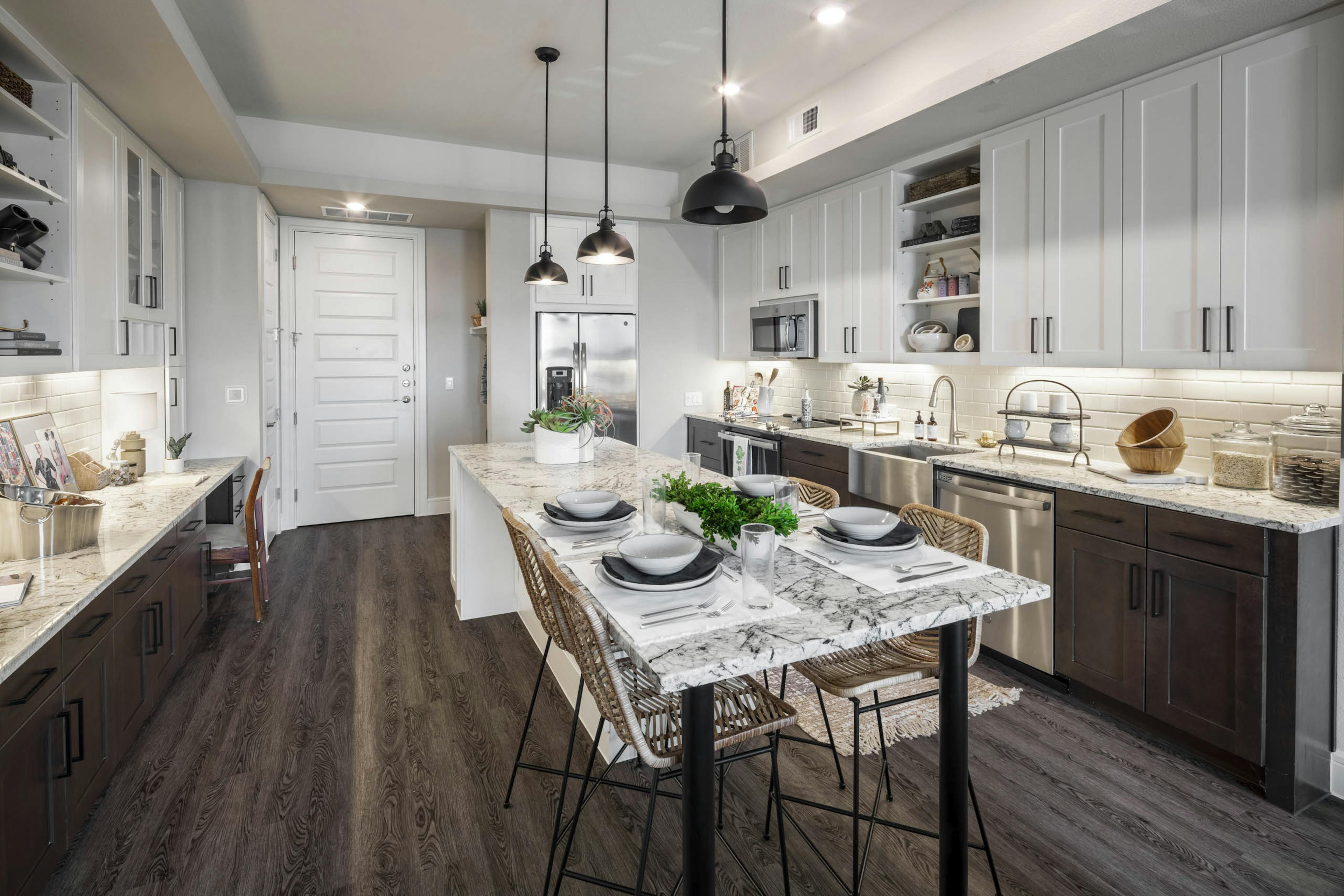 Apartment kitchen at AMLI Lakeline with dark wooden floors and a large kitchen island with gray granite countertops