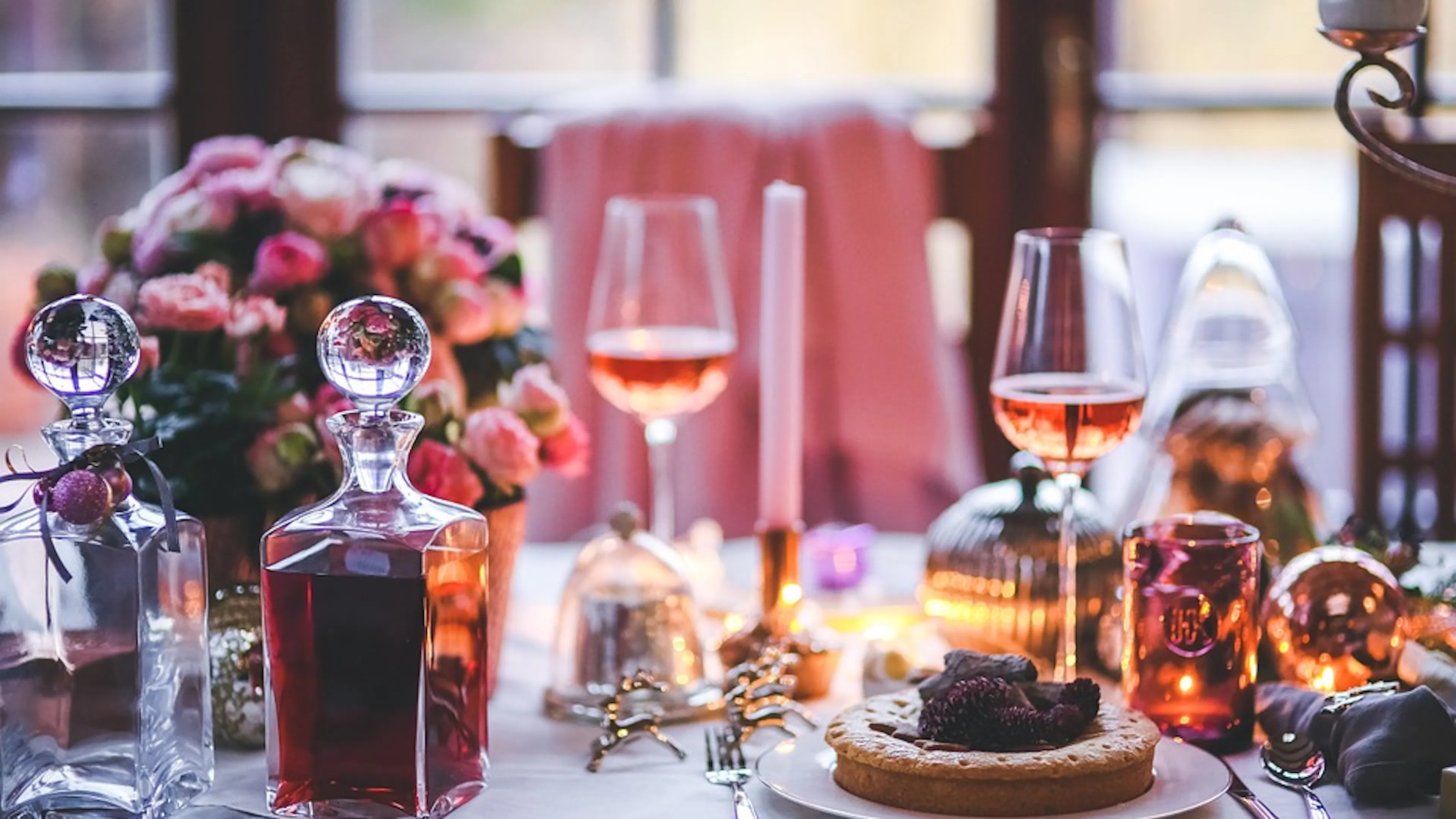 An elaborate table setting with wine and desserts scattered around on the white tablecloth