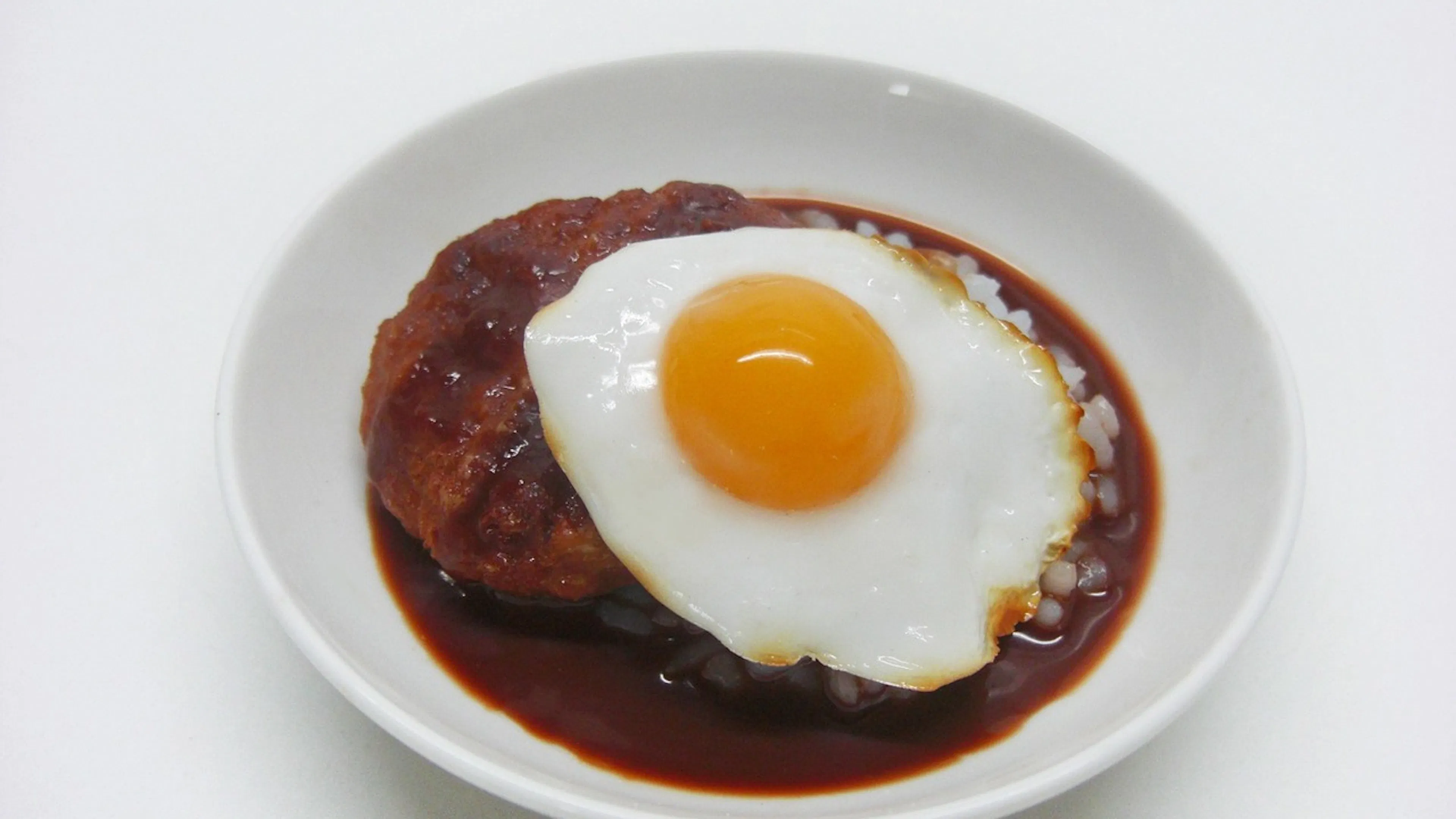 A bowl of loco moco made with rice and brown gravy with a fried egg on top