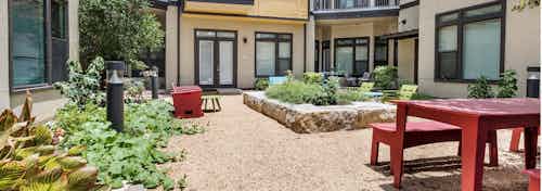 Exterior view of AMLI 5350 courtyard garden with raised red table with benches and surrounding vibrant green plants