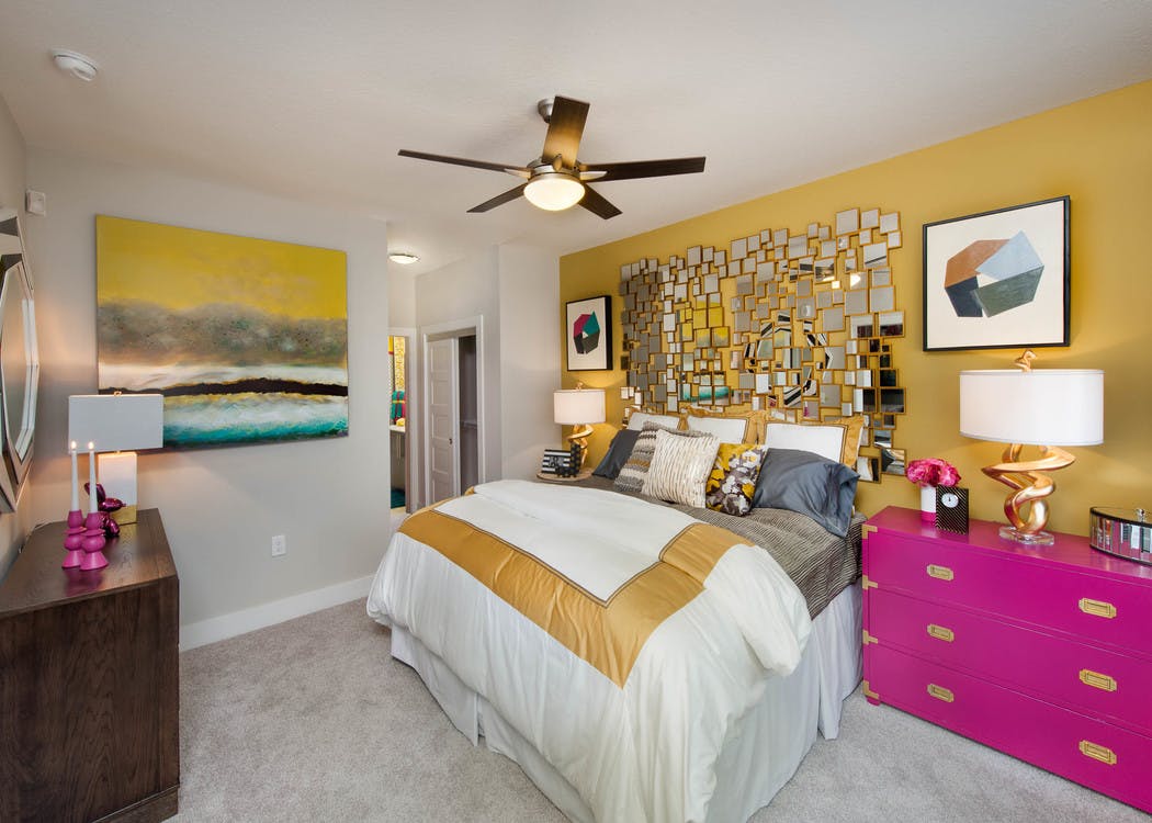 Interior of an AMLI Piedmont Heights bedroom with a gold wall while the others are grey with carpet and bright colorful decor