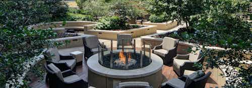 Rooftop firepit at AMLI River North with surrounding green folliage and wicker chairs centered around a firepit with a flame