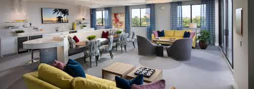 Rooftop view in the AMLI 8800 Resident Lounge seating area yellow accent furniture, TV on wall and entertaining kitchen