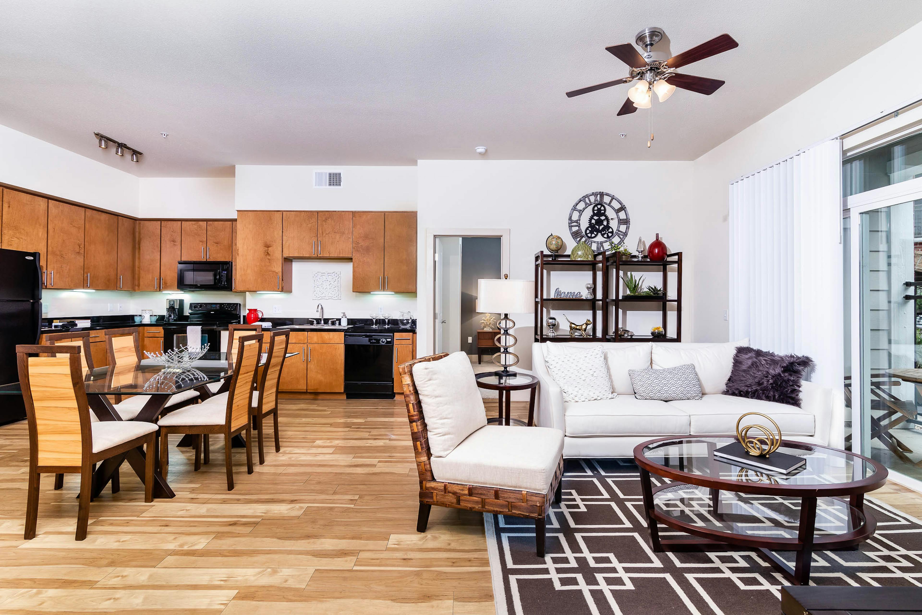 Interior view of a living room and kitchen at AMLI Park Avenue apartments with a dining room table and a plush white couch