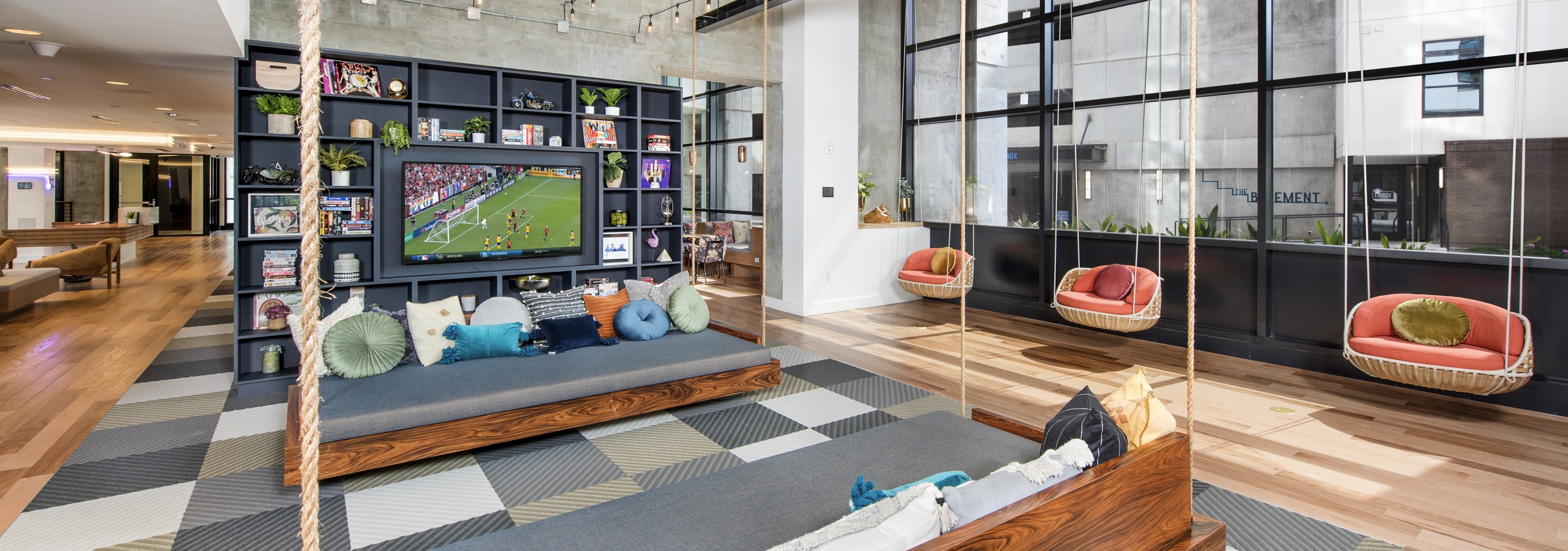 Interior view of AMLI Lenox clubhouse with three swings and seating with lots of colorful pillows and a flat screen TV