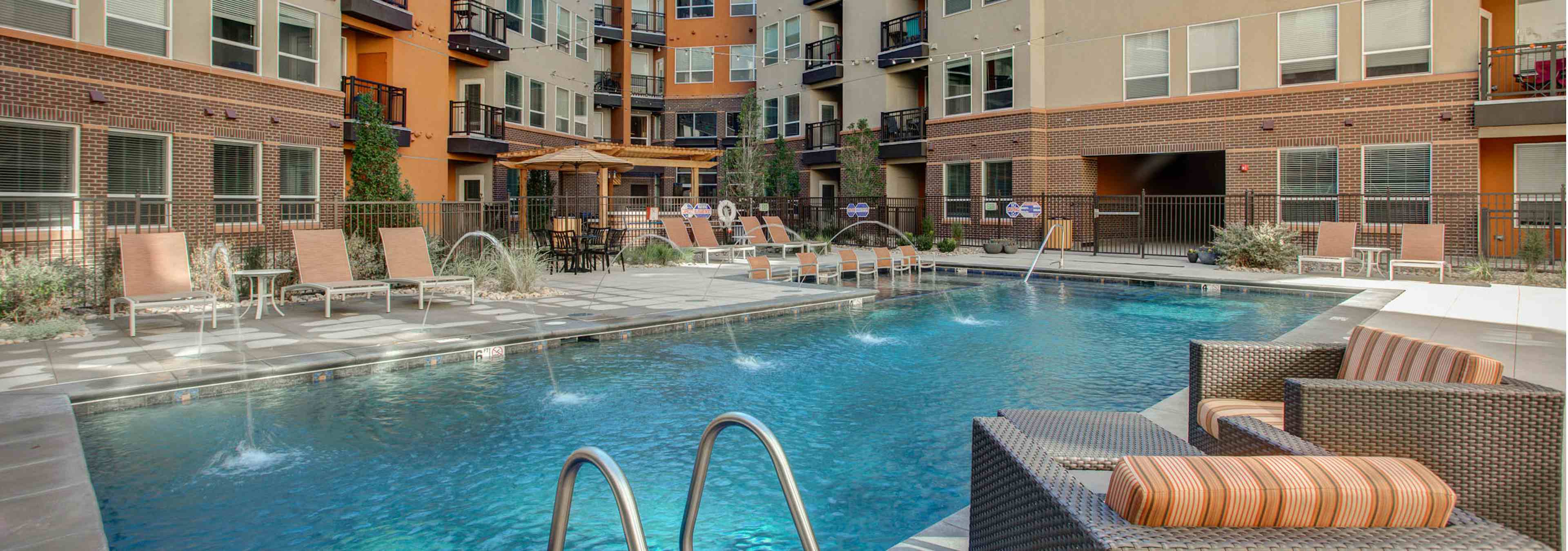 Exterior view of the pool at AMLI Riverfront Park apartments with padded lounge chairs and a view of the apartment building 