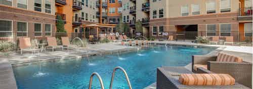 Exterior view of the pool at AMLI Riverfront Park apartments with padded lounge chairs and a view of the apartment building