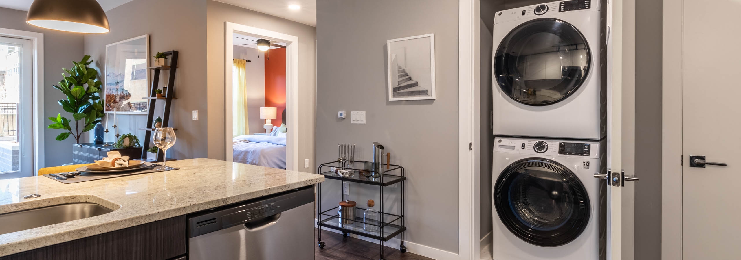 Close up view of closet door in AMLI at Uptown apartment kitchen opening to reveal modern white stacked washer and dryer
