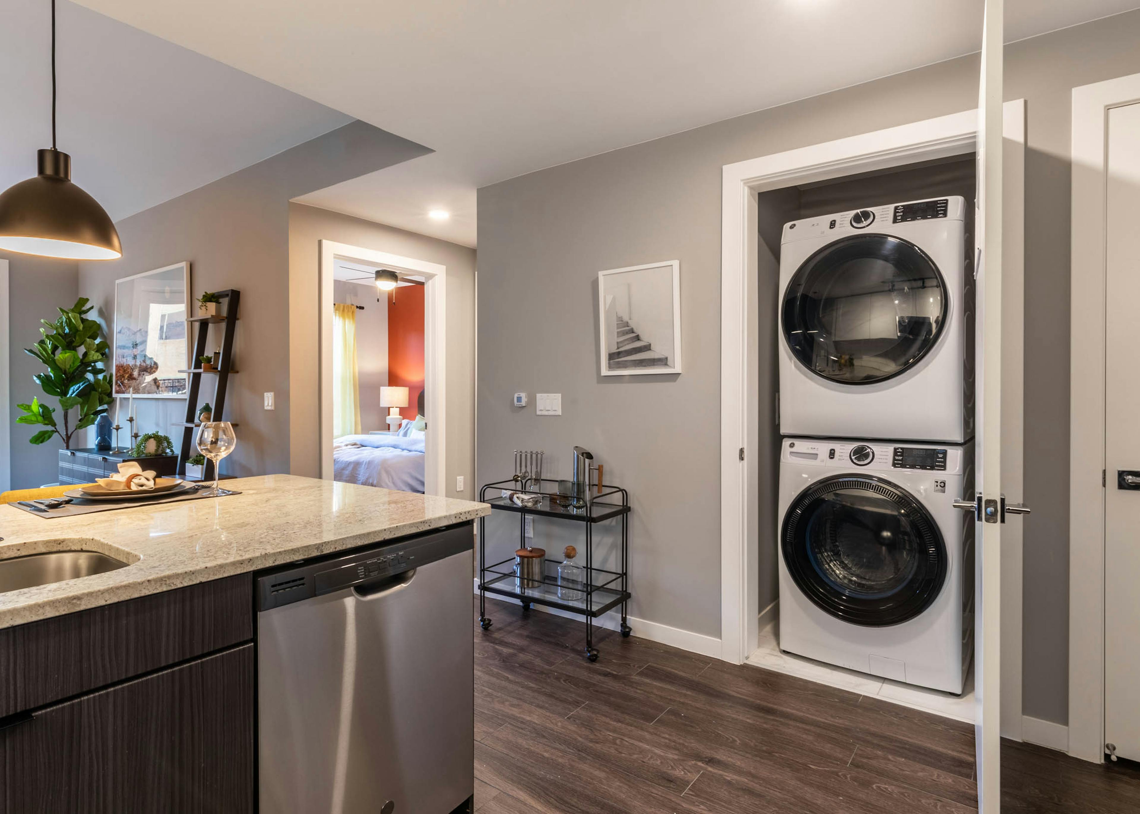 Close up view of closet door in AMLI at Uptown apartment kitchen opening to reveal modern white stacked washer and dryer