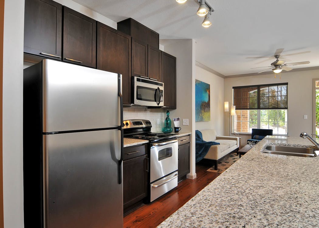 Kitchen at AMLI North Point with dark cabinets and stainless steel appliances and an island which connects to living space