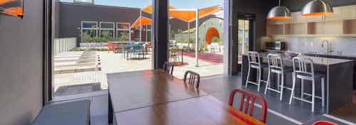 Interior view of the rooftop deck club room with kitchen island large wood community table and view of outdoor deck