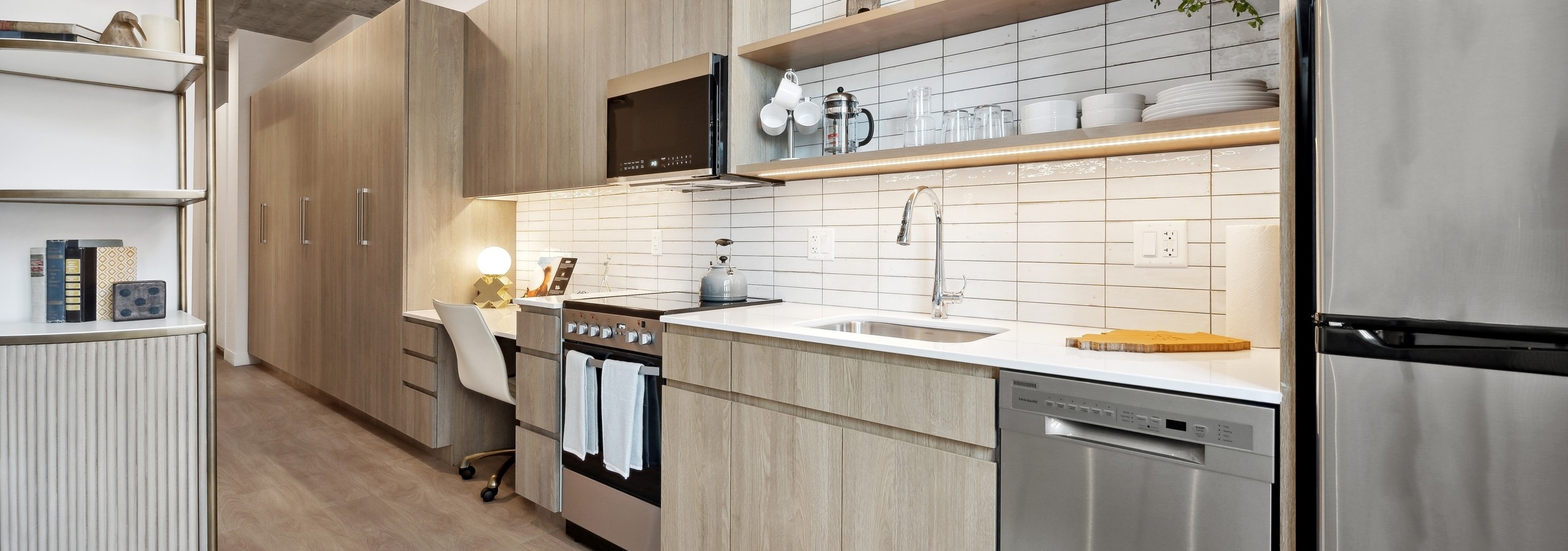 Kitchen with light wood cabinets and white tile backsplash and open shelving with distressed ceiling at AMLI 808 apartments