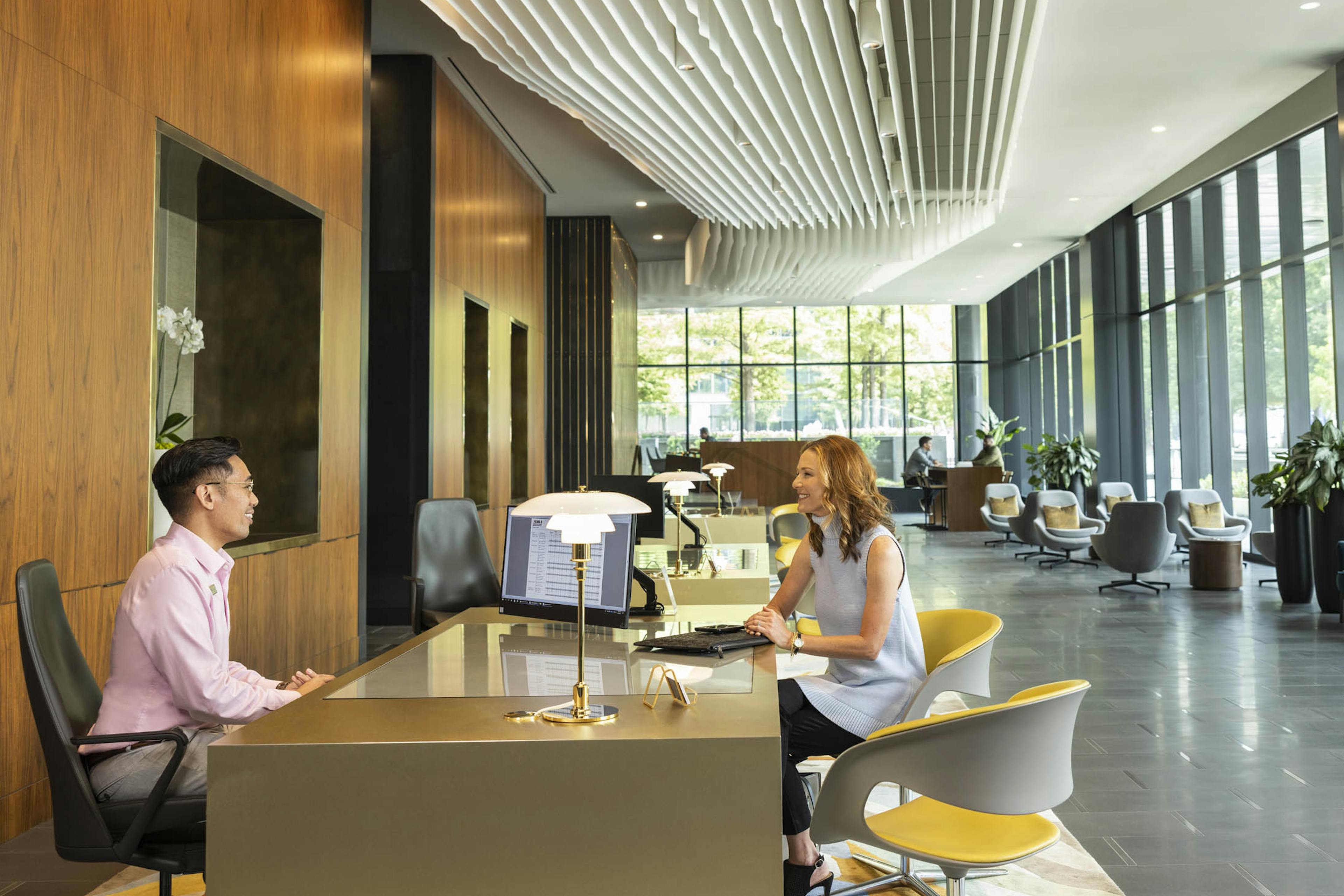 AMLI Fountain Place leasing agent and customers sitting in apartment leasing office surrounded by floor to ceiling windows
