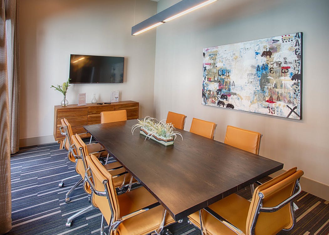 A conference room at AMLI Denargo Market apartments with a long table and chairs and a large piece of art and television