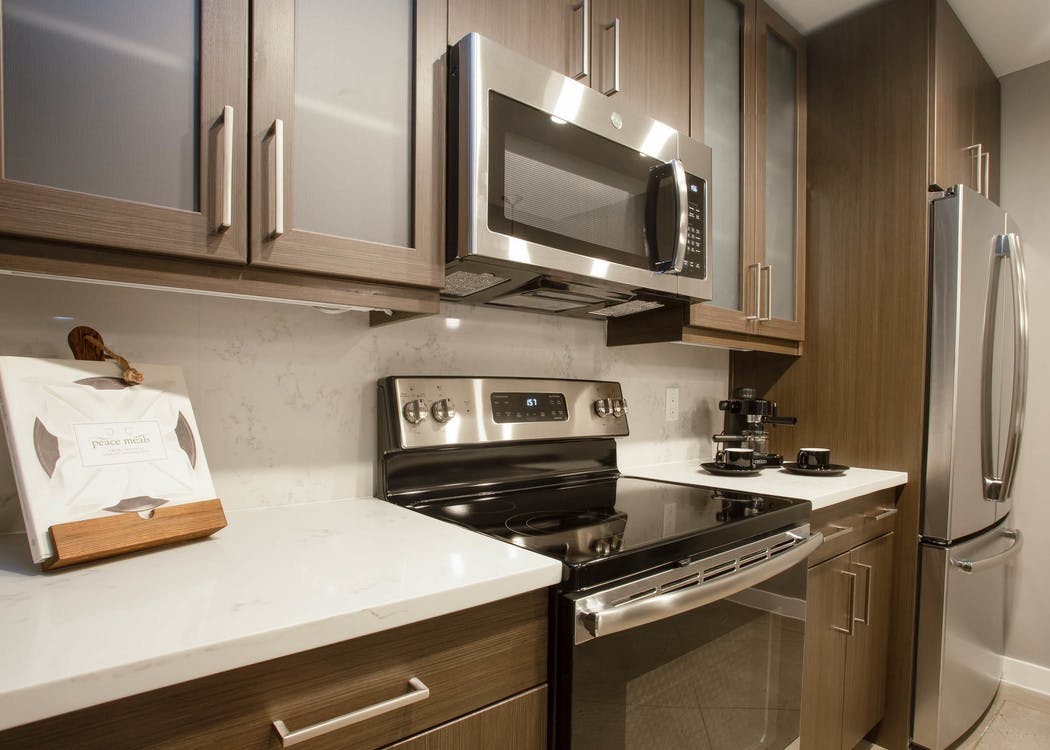 Close up of AMLI Downtown kitchen with white quartz countertops and brown cabinets and stainless steel appliances in background