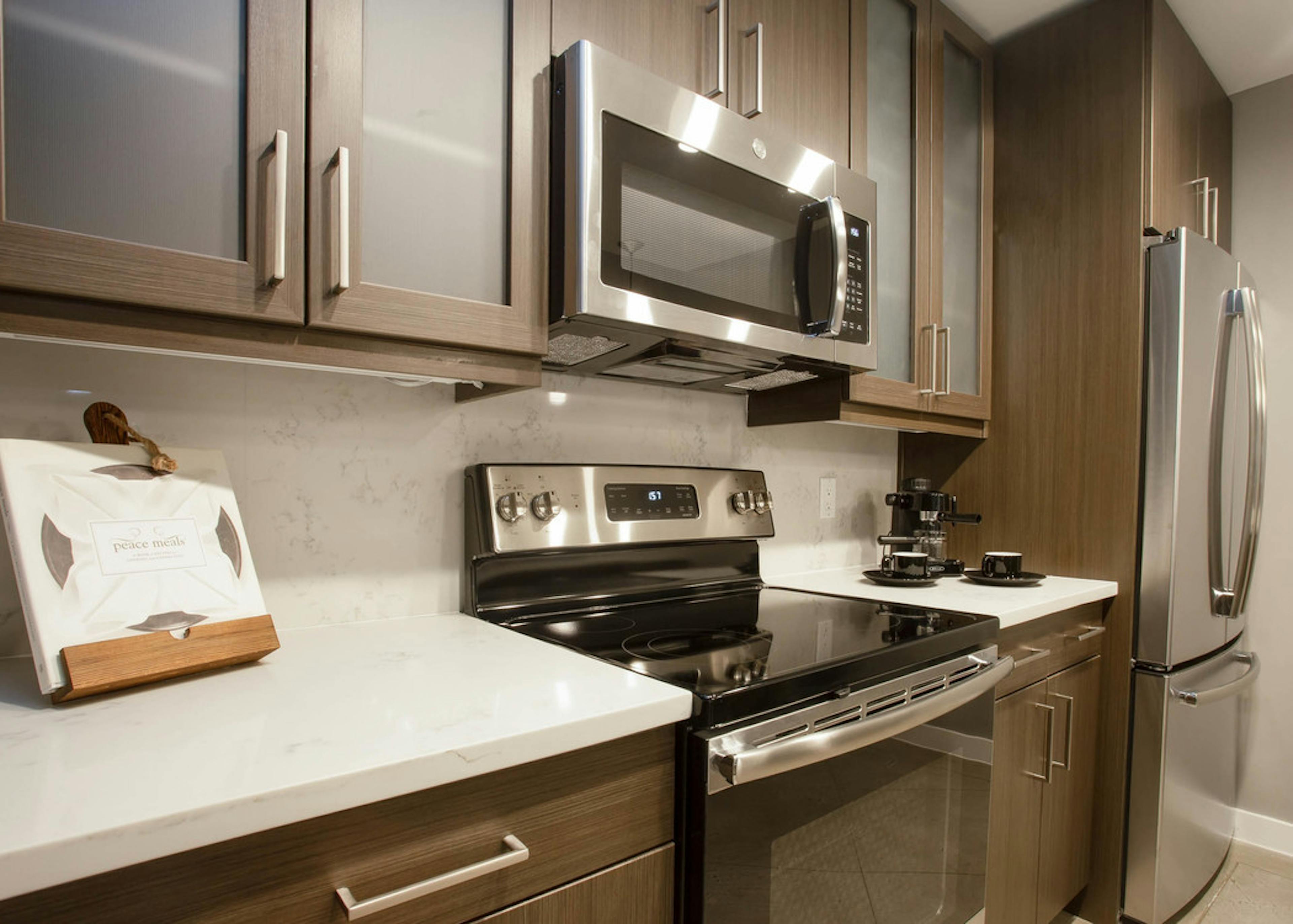 Close up of  AMLI Downtown kitchen with white quartz countertops and brown cabinets and stainless steel appliances in background