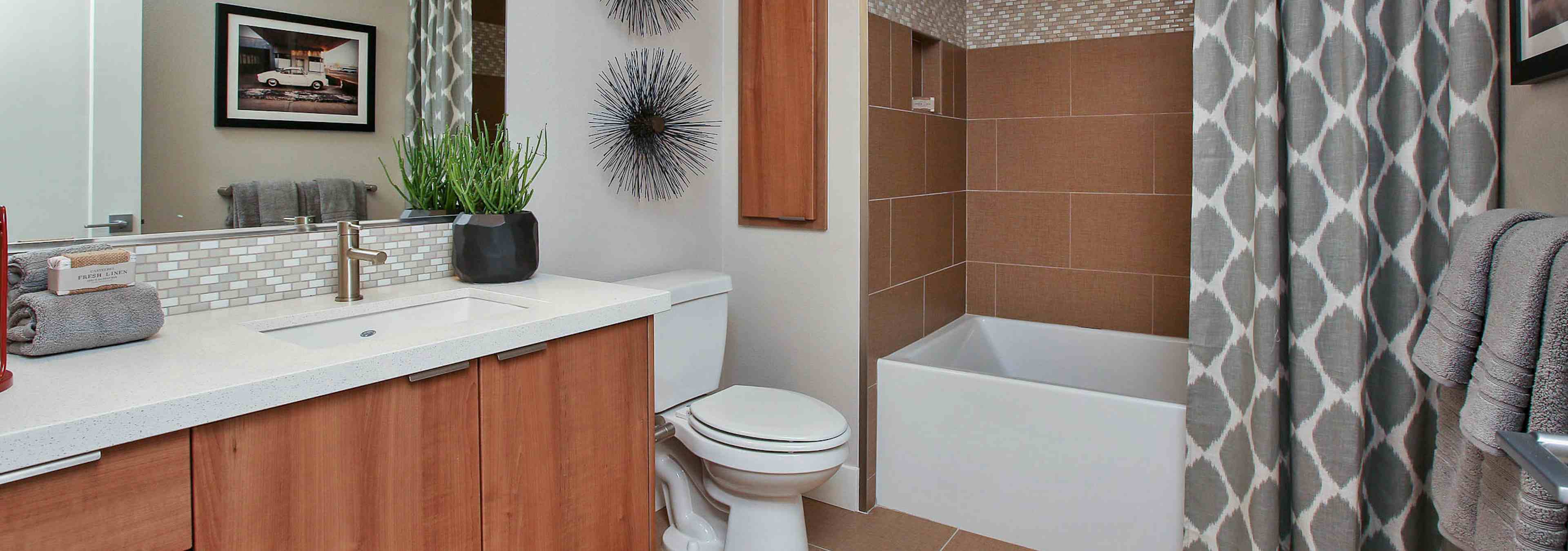 Interior view of AMLI Uptown Orange apartment bathroom with quartz countertop and large soaking tub with tile surround