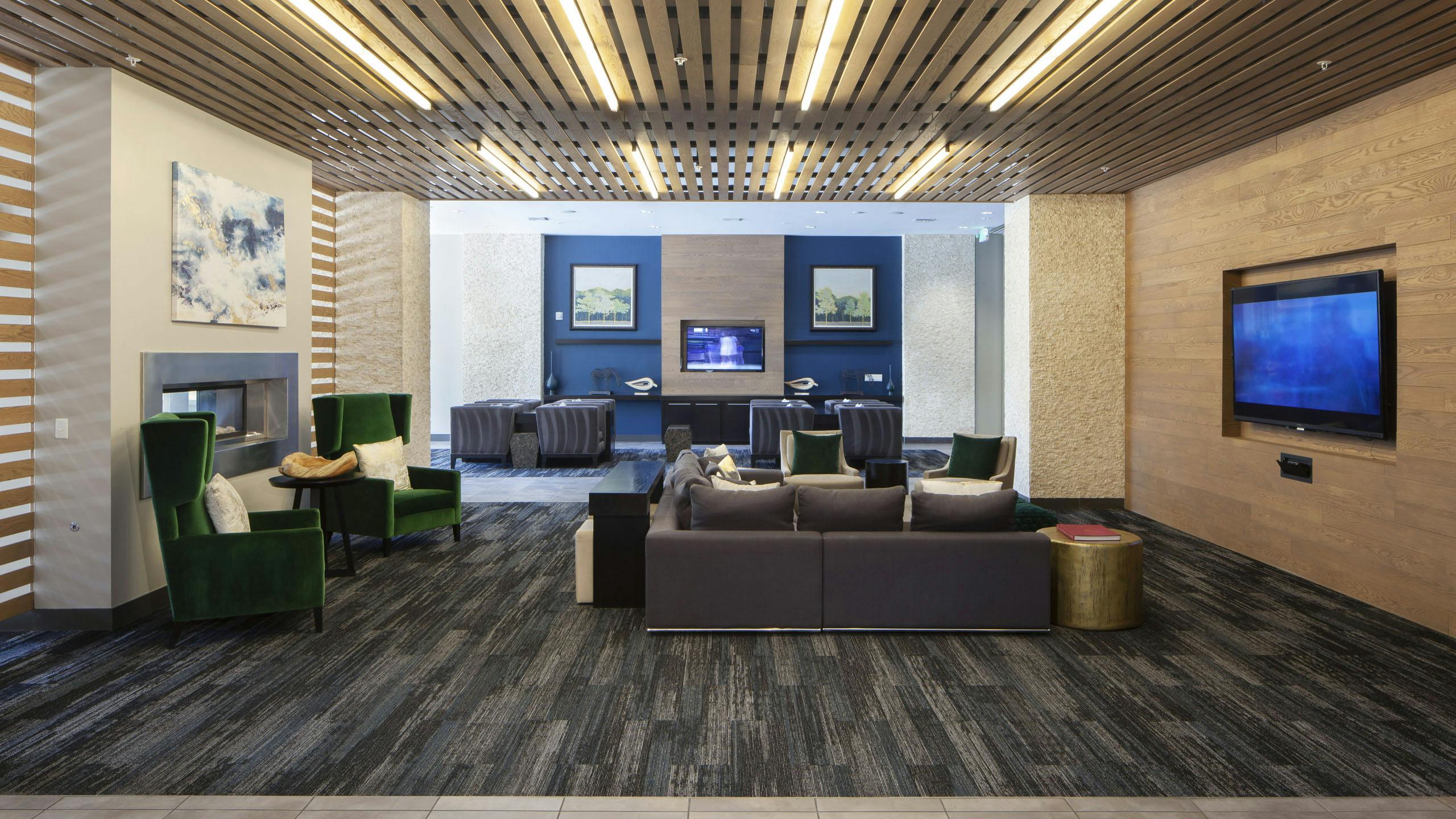 Interior of a clubroom with couches, several plush chairs and a fireplace and big screen TV at AMLI Cherry Creek apartments