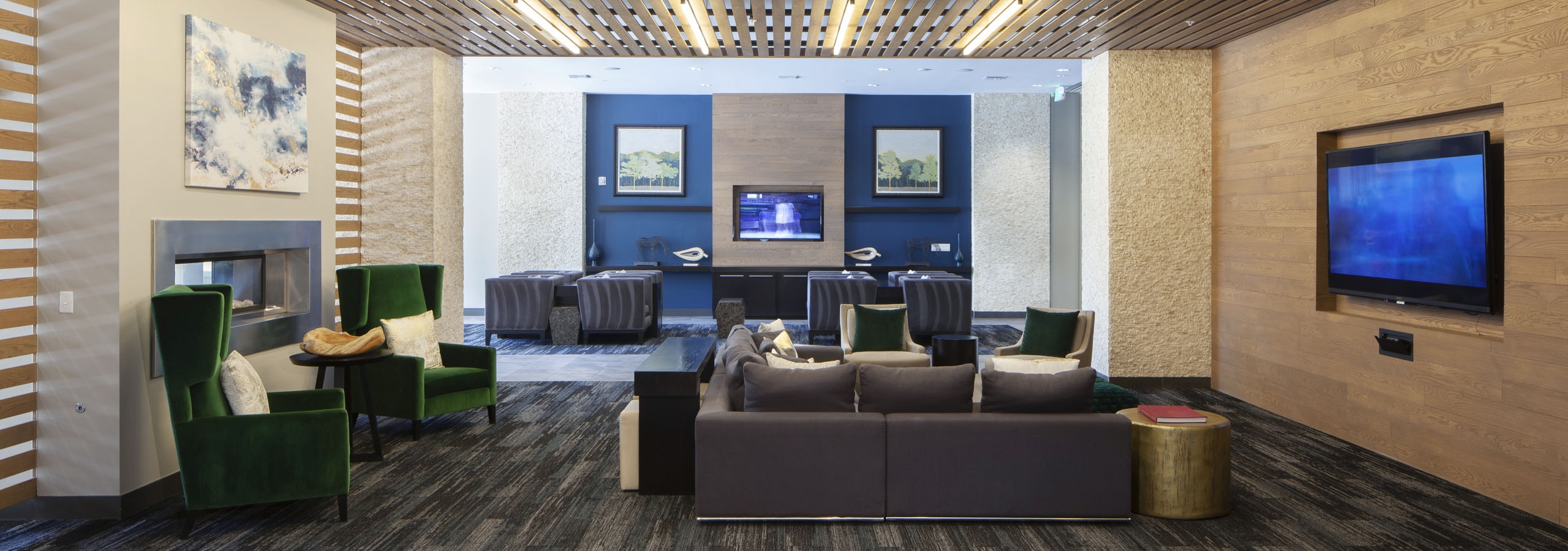 Interior of a clubroom with couches, several plush chairs and a fireplace and big screen TV at AMLI Cherry Creek apartments