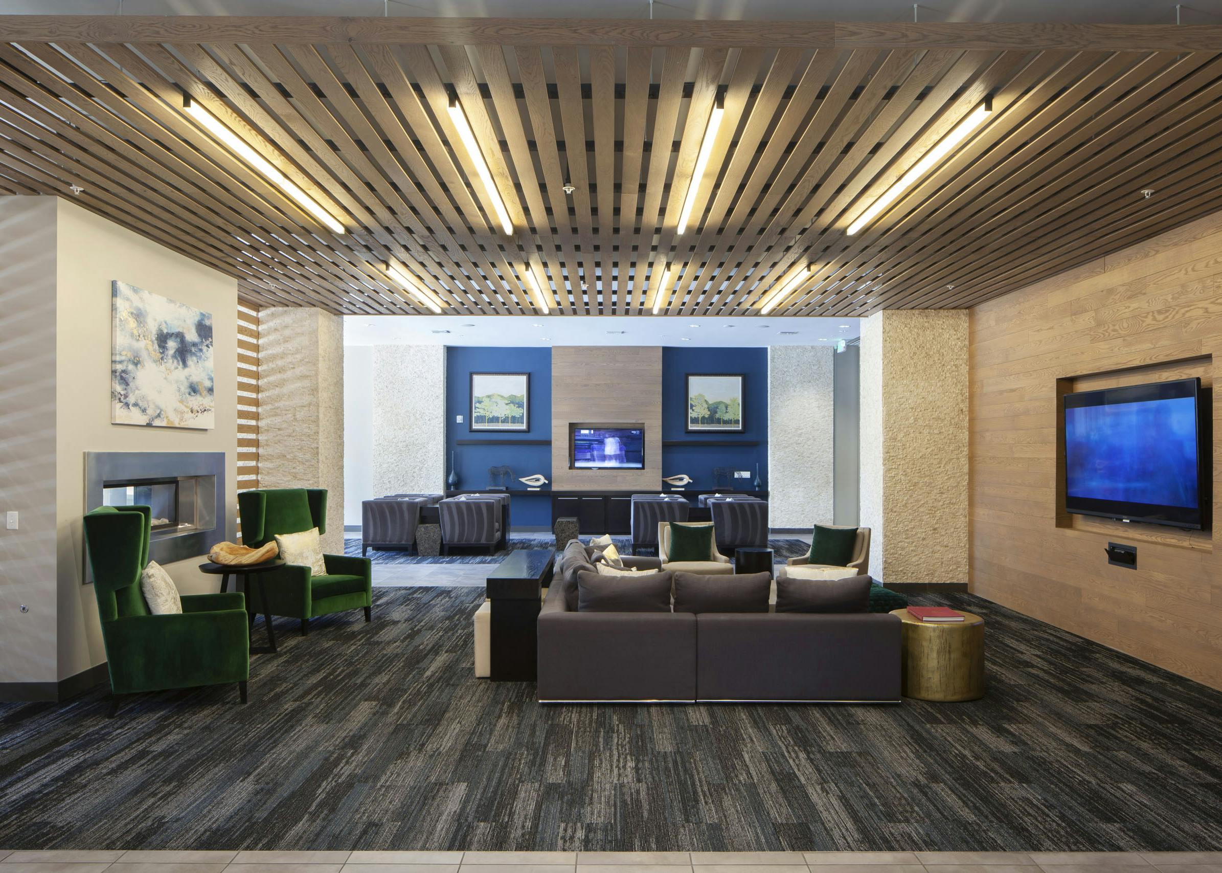 Interior of a clubroom with couches, several plush chairs and a fireplace and big screen TV at AMLI Cherry Creek apartments