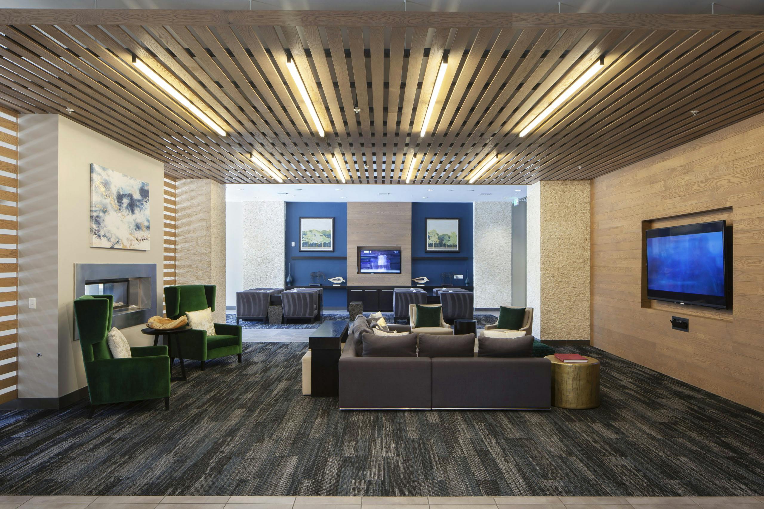 Interior of a clubroom with couches, several plush chairs and a fireplace and big screen TV at AMLI Cherry Creek apartments