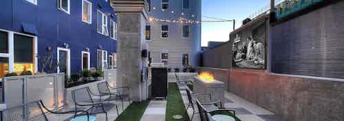 Outdoor pull down movie theater with fire grass turf and plenty of seating with string lights