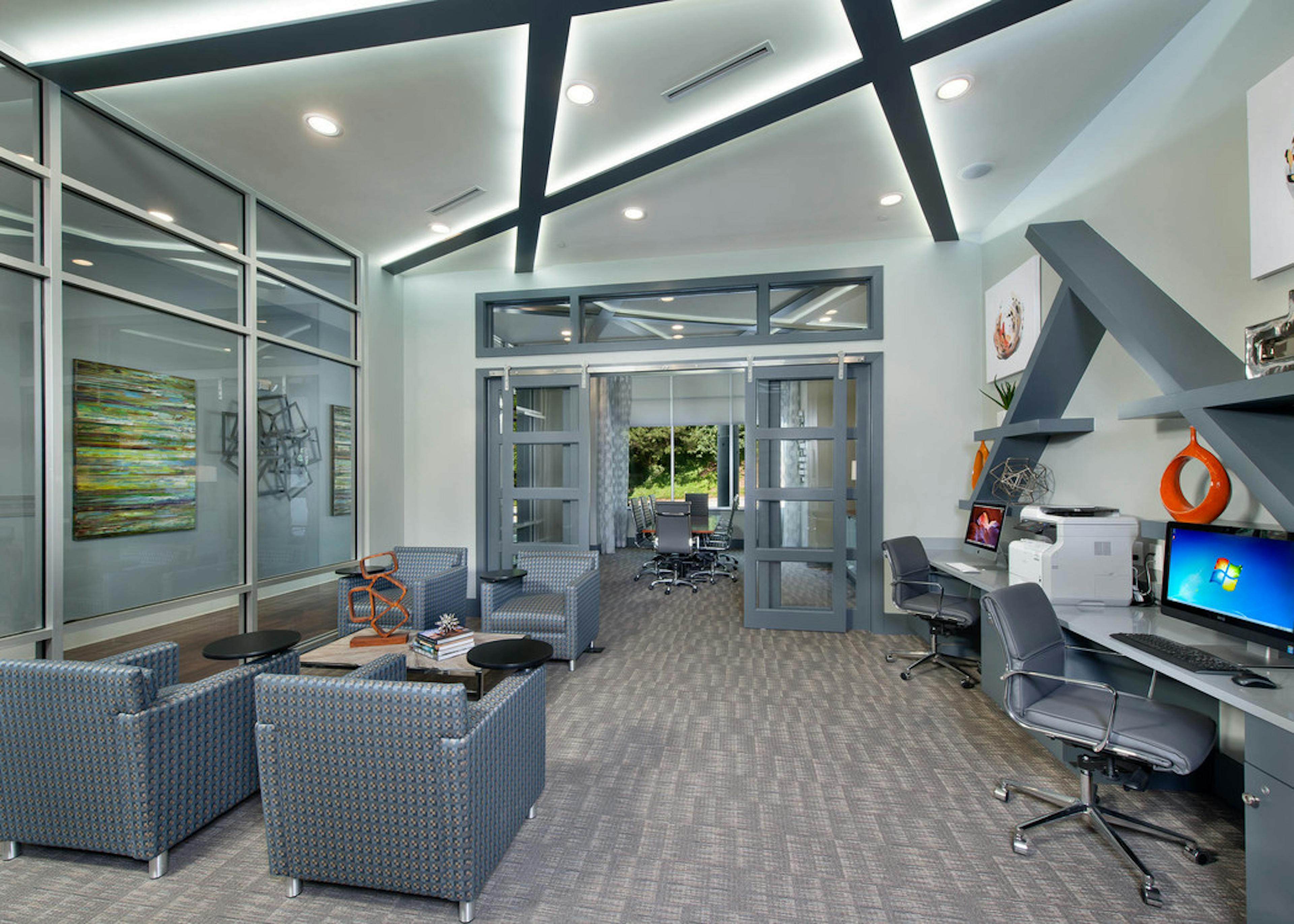 AMLI Piedmont Heights business center showing desk spaces with computers and a printer along with rolling chairs and seating