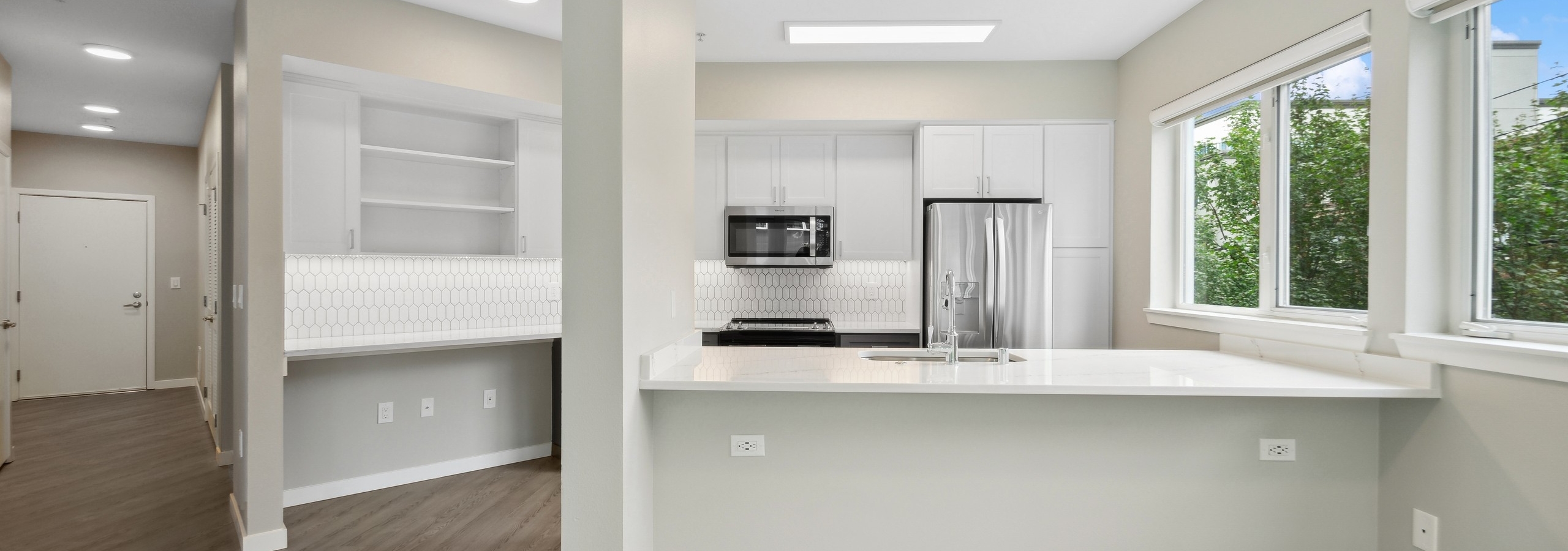 Kitchen at AMLI 535 with sink set in island and white countertops and cabinets and stainless steel appliances